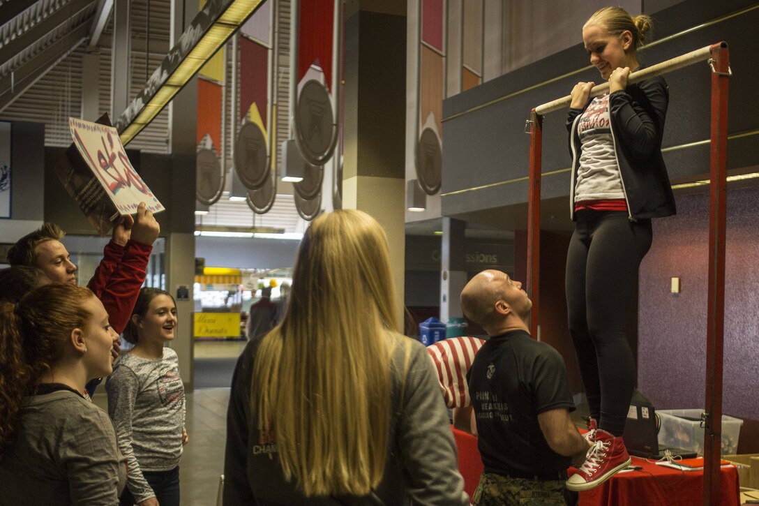 Gunnery Sgt. Michael Sterba, staff noncommissioned officer in charge for Recruiting Sub-Station Casper, lifts an attendee of the Wyoming State High School Basketball Championship on to a pull-up bar to commence a flex-arm hang at the Casper Event Center March 11, 2016. The Casper Event Center hosts multiple events for high school sports throughout the year.