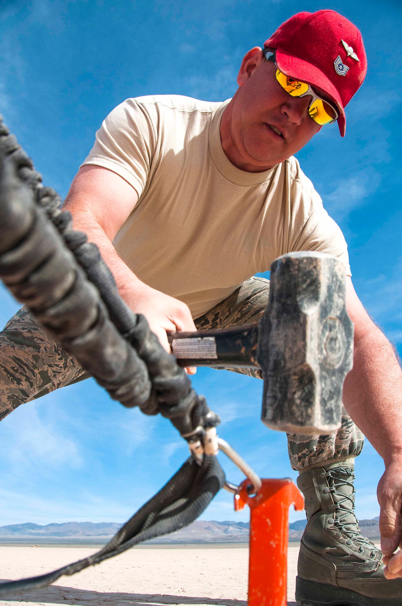Tech. Sgt. Blane Lopez, 80th Aerial Port Squadron aerial delivery, hammers stakes to set up markers for a landing space in desert near Nellis Air Force Base, Nev. during Red Flag 16-2 March 5, 2016. Capable of using unprepared runways for takeoffs and landings, the C-130 was originally designed as a troop, medivac, and cargo transport aircraft. (U.S. Air Force photo/Staff Sgt. Daniel Phelps)
