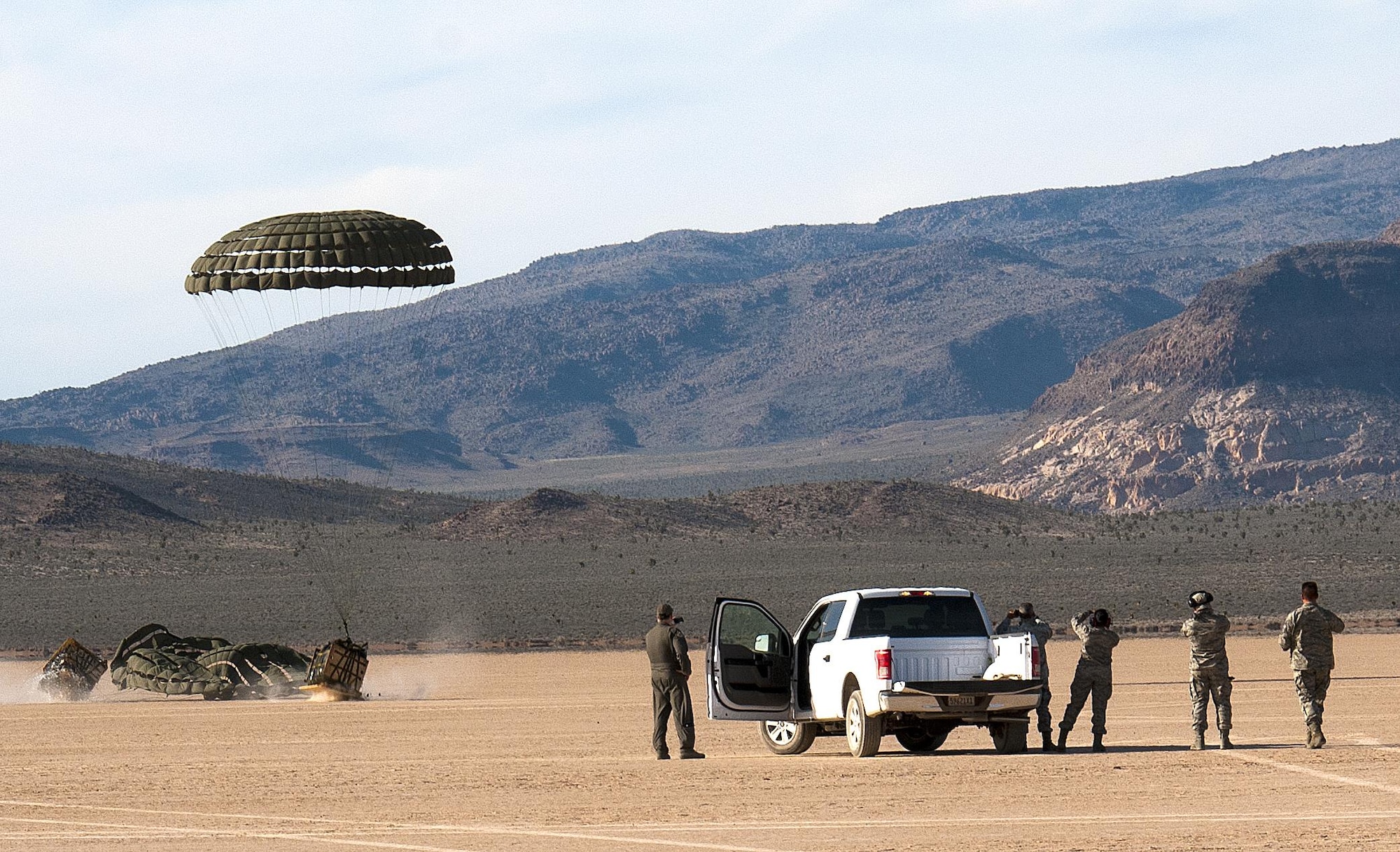 Members from the 94th Airlift Wing await for supplies dropped from a C-130 Hercules in a drop zone during Red Flag 16-2 in the desert near Nellis Air Force Base, Nev., March 5, 2016. Red Flag is an exercise hosted by Nellis Air Force Base, Nev. that provides aircrews an opportunity to experience realistic, stressful combat situations in a controlled environment to increase mission capability. (U.S. Air Force photo/Staff Sgt. Daniel Phelps)
