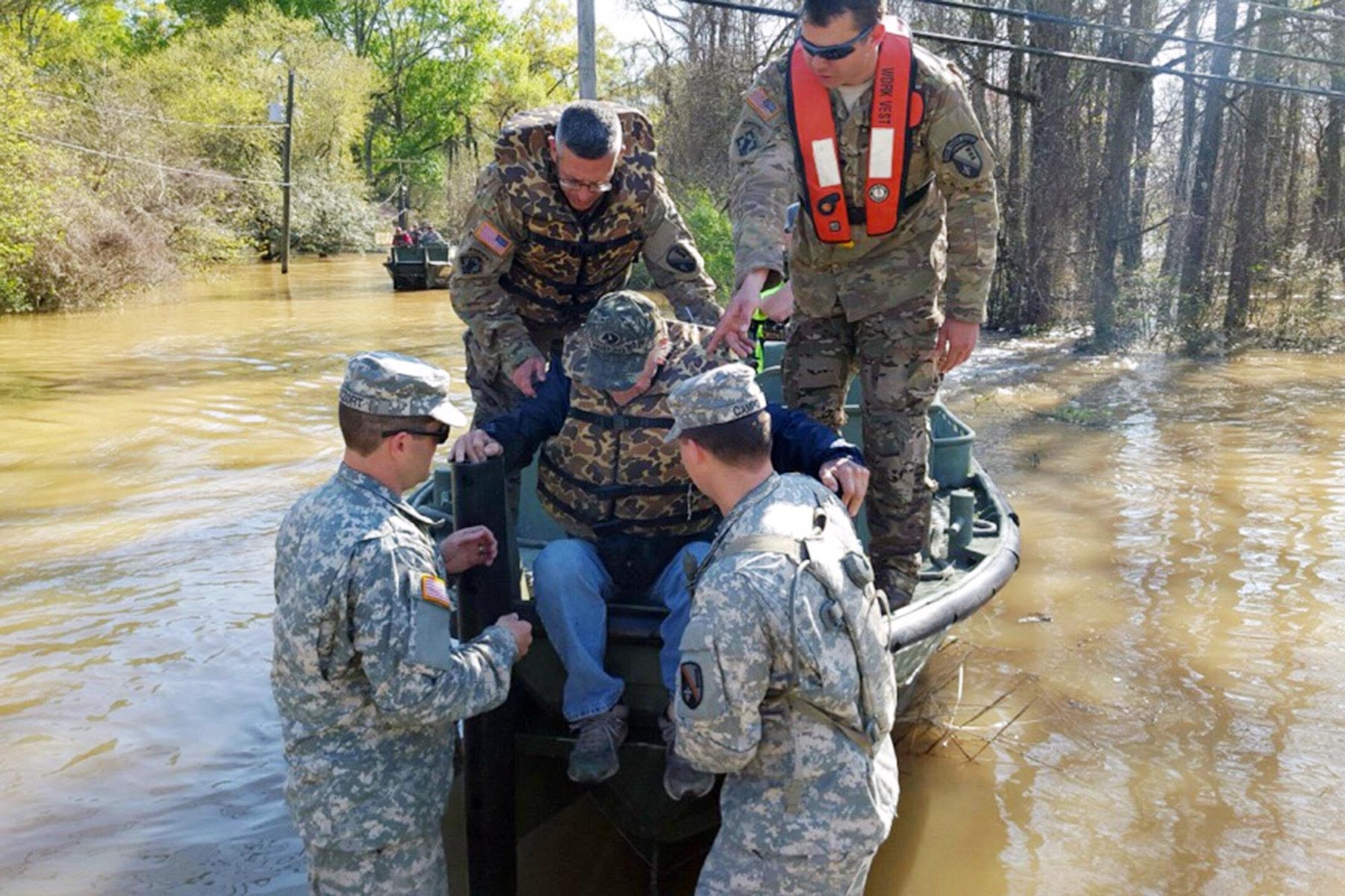 Soldiers help a flood victim from a rescue boat in Ponchatoula, La., March 13, 2016. The soldiers are assigned to the Louisiana National Guard’s 2225th Multi-Role Bridge Company, 205th Engineer Battalion. Louisiana National Guard photo by 1st Lt. Rebekah Malone