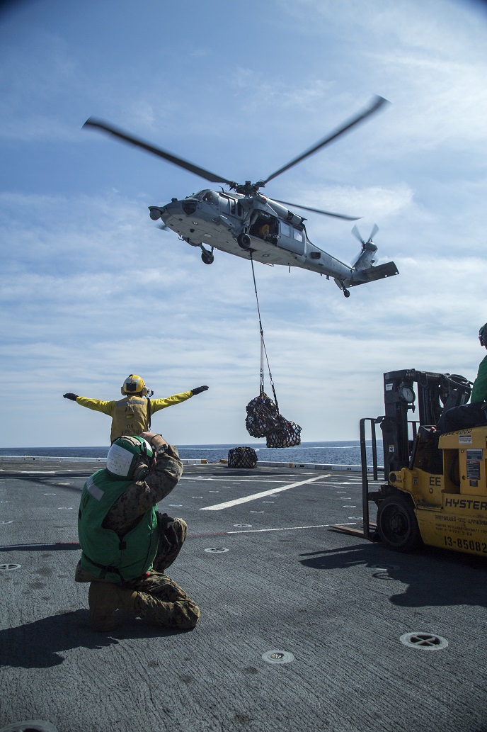 U.S. Marine Sgt Tyler Gregory, combat camera photographer, 13th Marine Expeditionary Unity, documents U.S. Sailors of the USS New Orleans conducting a resupply at sea with Helicopter Sea Combat Squadron 23 during their Western Pacific Deployment, March 5, 2016. More than 4,500 Marines and Sailors from the Boxer Amphibious Ready Group, 13th Marine Expeditionary Unit team are currently transiting the Pacific Ocean toward the U.S. 7th Fleet area of operations during a scheduled deployment. (U.S. Marine Corps photo by Sgt. Hector de Jesus/Released)