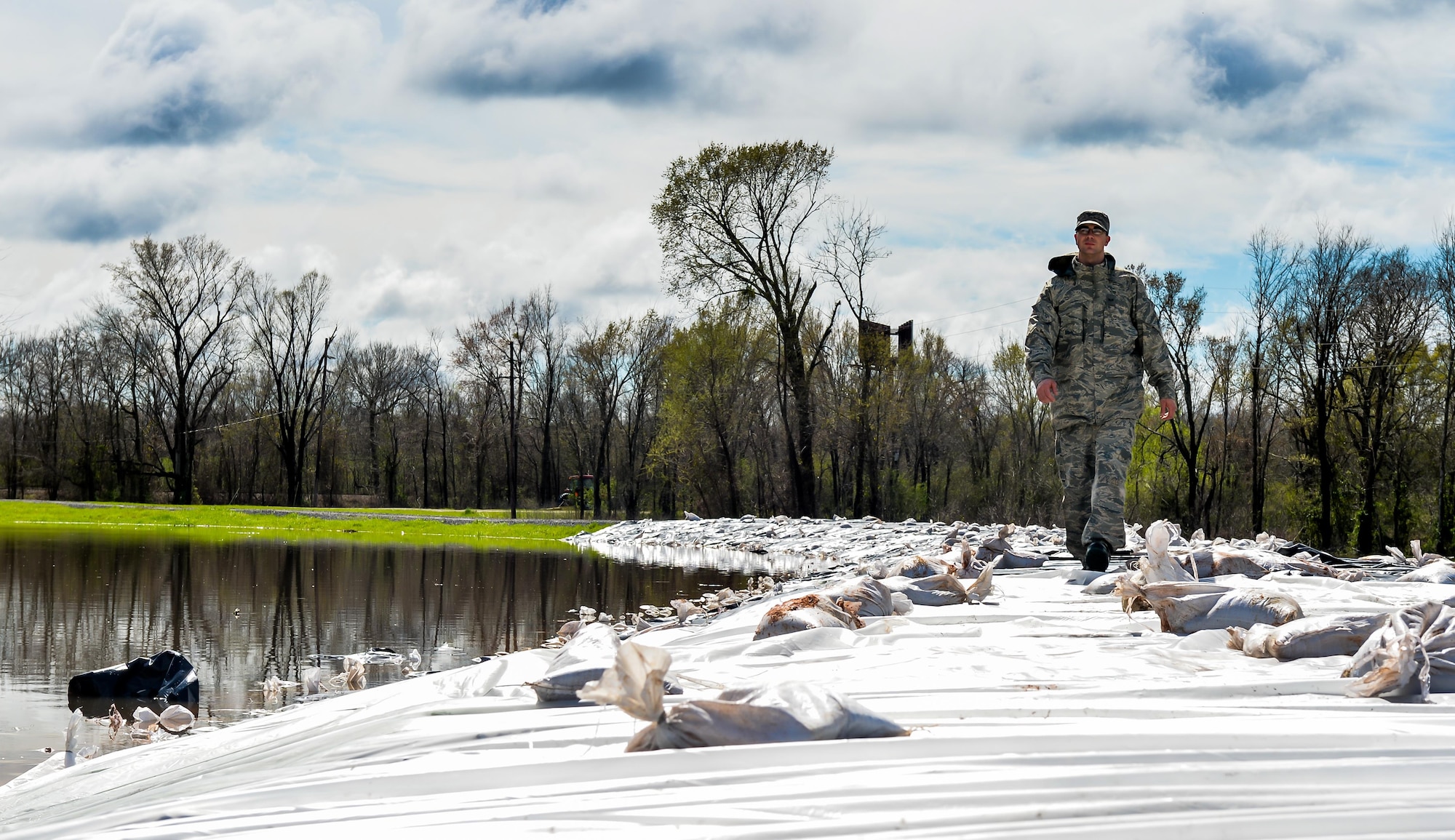 An Airman with the 2nd Logistic Readiness Squadron surveys a newly covered portion of the levee in Bossier City, La. March 10, 2016.  The plastic and sandbag barrier protected the Red Chute Bayou levee from potential corrosion caused by the overflowing river. (U.S. Air Force photo/Senior Airman Mozer O. Da Cunha)