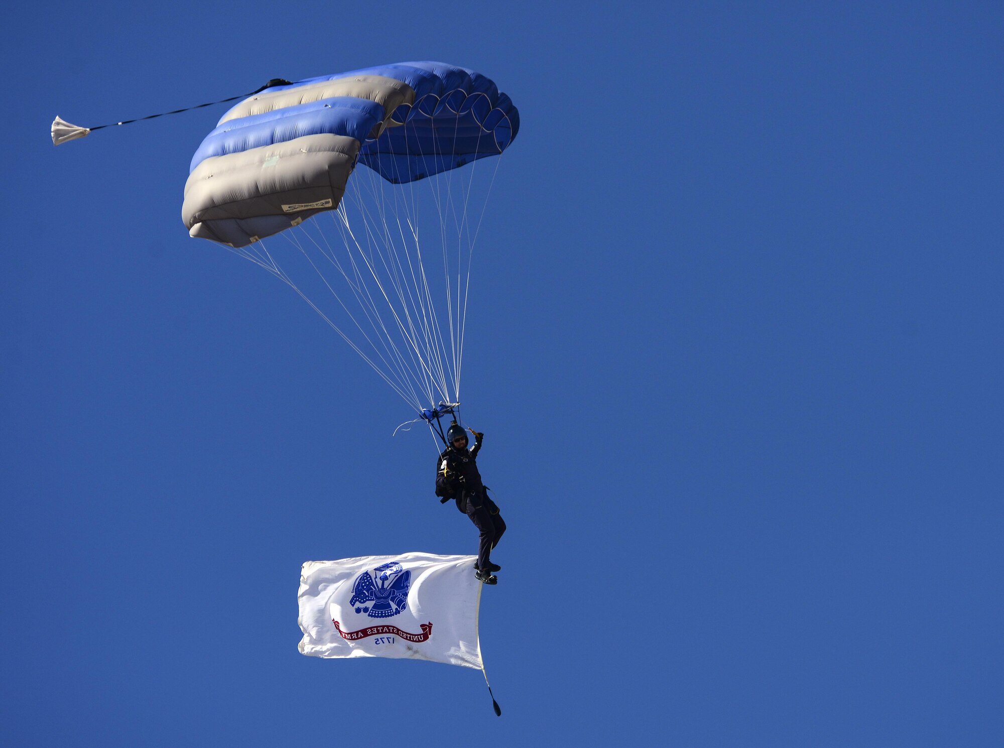 U.S. Air Force Lt. Col. Sean Baerman, 98th Flying Training Squadron director of operations and member of USAF Parachute Team “Wings of Blue,” parachutes to the flight line during the Thunder and Lightning over Arizona Open House event at Davis-Monthan Air Force Base, Ariz., March 13, 2016. During their performance, five WOB teammates flew respective flags dedicated to each U.S. Armed Service. (U.S. Air Force photo by Senior Airman Chris Drzazgowski/Released)