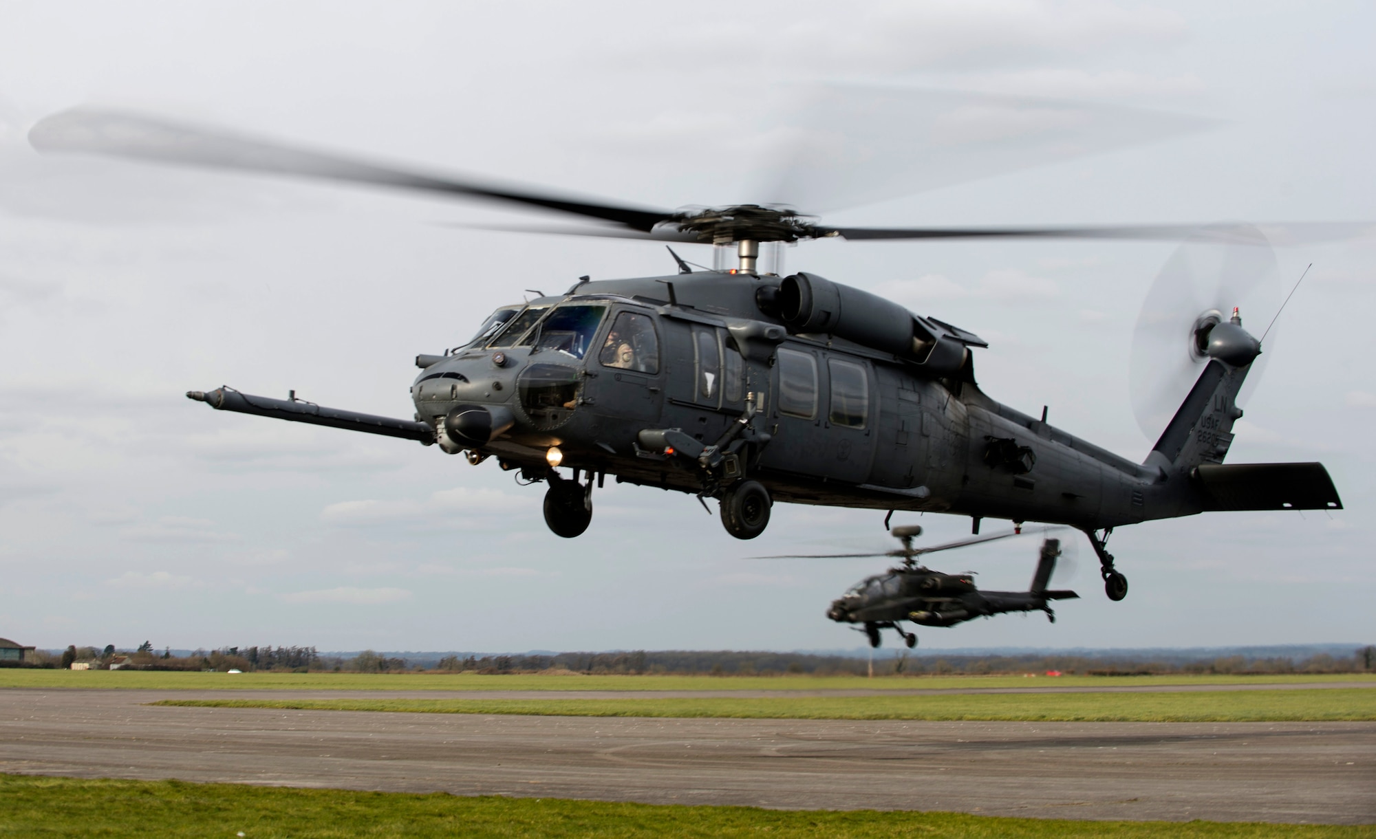 An HH-60G Pave Hawk from the 56th Rescue Squadron and a British Army AH-64 Apache from 663 Squadron, 3 Regiment Army Air Corps, take off from the flightline during exercise Voijek Valour at Hullavington Airfield, England, Feb. 29, 2016. The exercise included six helicopters, 250 British Army soldiers and more than a dozen jets conducting scenarios across Salisbury Plain. (U.S. Air Force photo/Staff Sgt. Emerson Nuñez)
