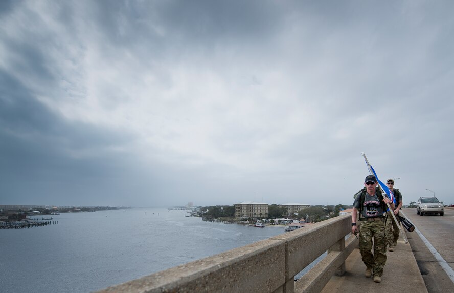 A two-man team of Marines traverses across Brooks Bridge March 11 in Fort Walton Beach, Fla.  The team is part of the Marines’ 770-mile ruck march to honor the fallen Marines who died in last year’s Blackhawk crash.  The march travels from Navarre to Camp Lejeune, N.C.  The lead Marine carries the unit’s flag while the second Marine carries a boat paddle found in the wreckage of the crash.  (U.S. Air Force photo/Samuel King Jr.)  