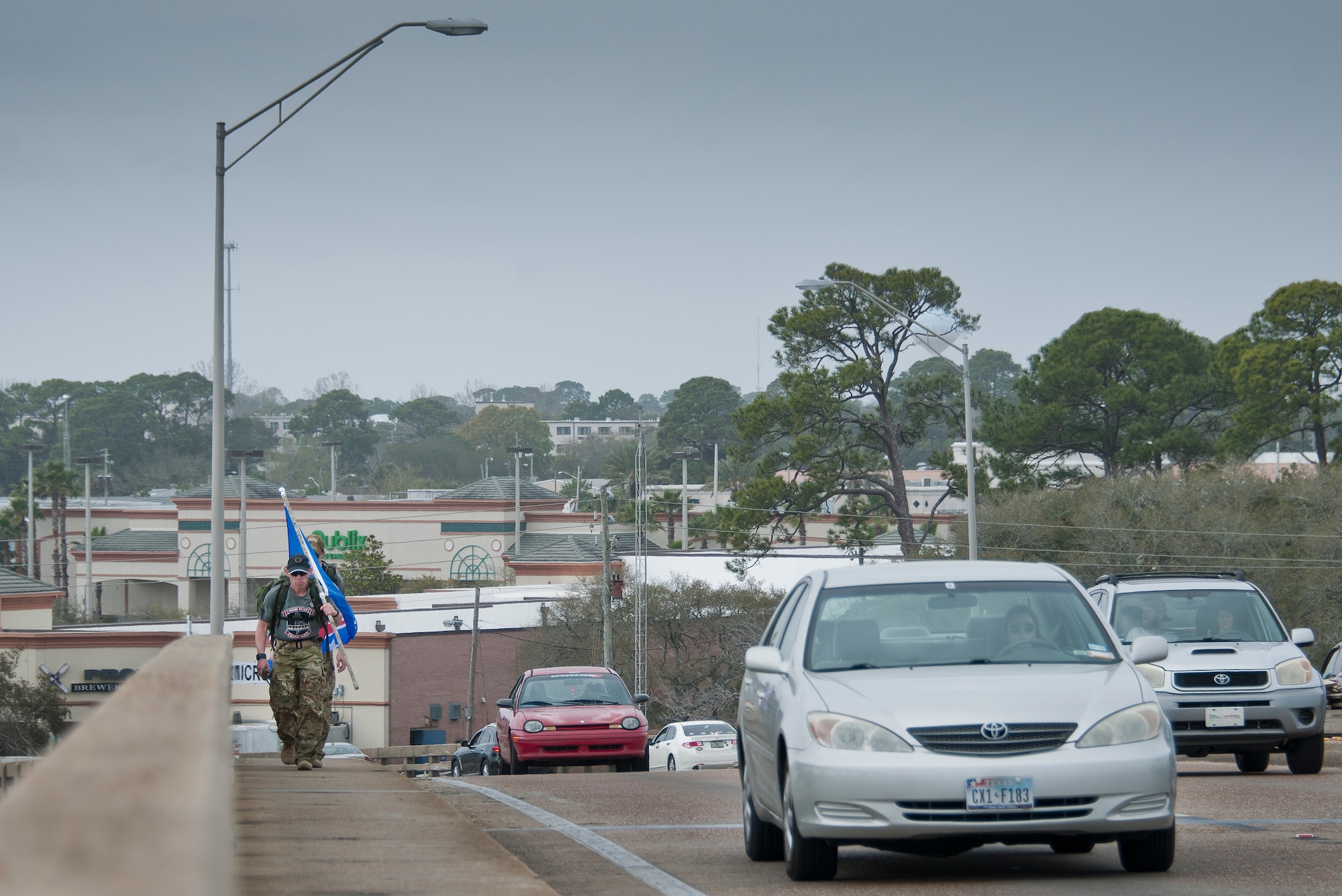 A two-man team of Marines traverses across Brooks Bridge March 11 in Fort Walton Beach, Fla.  The team is part of the Marines’ 770-mile ruck march to honor the fallen Marines who died in last year’s Blackhawk crash.  The march travels from Navarre to Camp Lejeune, N.C.  The lead Marine carries the unit’s flag while the second Marine carries a boat paddle found in the wreckage of the crash.  (U.S. Air Force photo/Samuel King Jr.)  