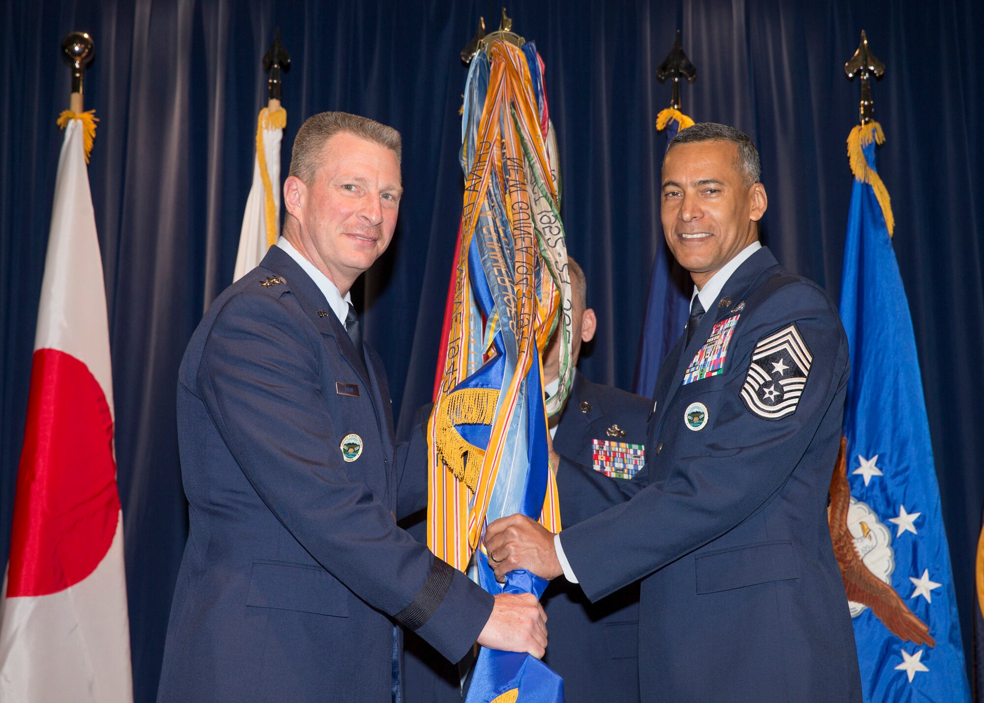 Lt. Gen. John Dolan, United States Forces Japan and 5th Air Force commander, passes the 5th AF guidon to Chief Master Sgt. Terrence Greene, USFJ and 5AF incoming command chief, during a change of responsibility ceremony at Yokota Air Base, Japan, March 10, 2016. Dolan presided over the ceremony. (U.S. Air Force photo by Osakabe Yasuo/Released)