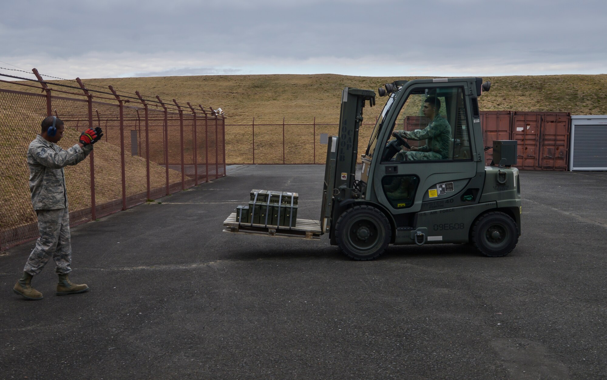 Airman Jeremy Pabst, 374th Maintenance Squadron Munitions Flight crew member, is guided by Senior Airman Damien Pittman, 374 MXS MUNS munitions stockpile surveillance crew member, as he drives a forklift to place a pallet to be picked-up at Yokota Air Base, Japan, Feb. 24, 2016. The flight is responsible for the accountability, storage and handling of munition assets at Yokota. (U.S. Air Force photo by Senior Airman David Owsianka/Released)