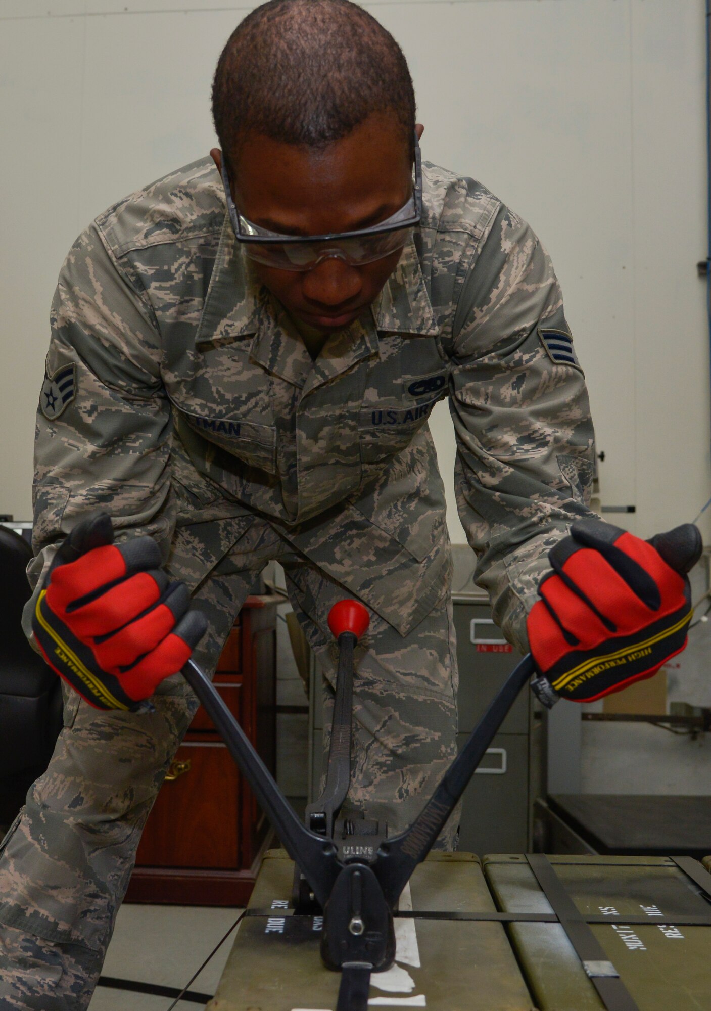 Senior Airman Damien Pittman, 374th Maintenance Squadron Munitions Flight munitions stockpile surveillance crewmember, uses a banning crimper to tighten a clip onto a strap on a container at Yokota Air Base, Japan, Feb. 24, 2016. Tightening straps onto the containers ensures they will not be tampered with prior to arriving at their next destination. (U.S. Air Force photo by Senior Airman David Owsianka/Released)