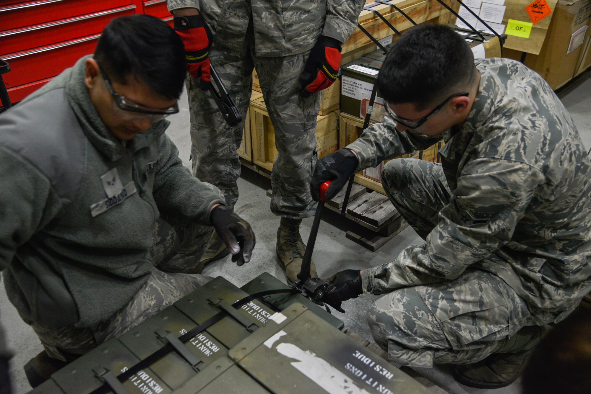 Members of the 374th Maintenance Squadron Munitions Flight tighten a strap on containers holding expended countermeasure flares at Yokota Air Base, Japan, Feb. 24, 2016. The C-130 Hercules use M-206 countermeasure flares to counter infrared homing surface-to-air missiles or air-to-air missiles. (U.S. Air Force photo by Senior Airman David Owsianka/Released)