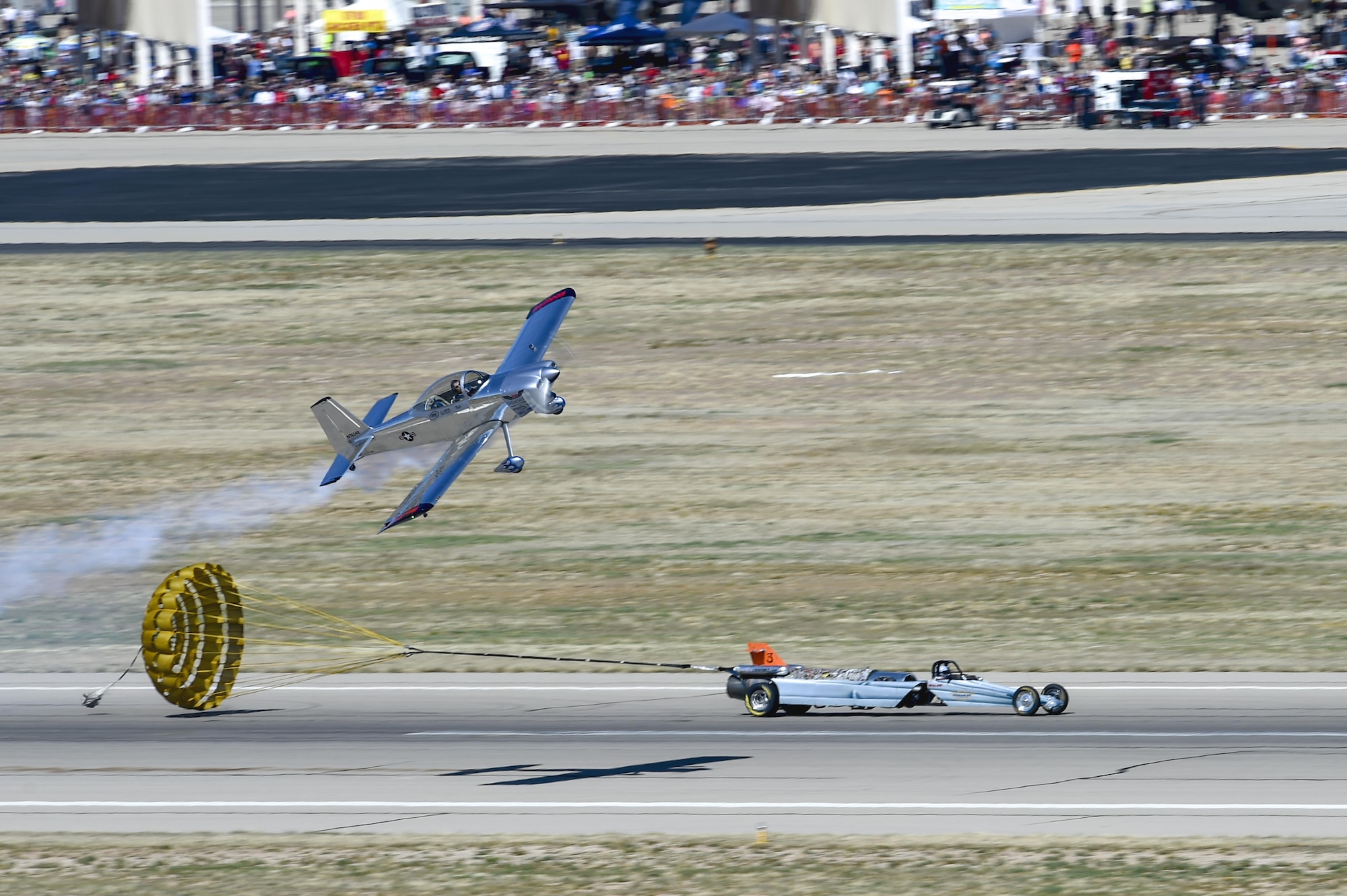 Bill Braack deploys the parachute to slow the Smoke-N-Thunder Jet Car, after racing Joe Shetterly, in a Van’s RV-8 aerobatic plane, on the runway during the Thunder and Lightning over Arizona Open House at Davis-Monthan Air Force Base, Ariz., March 12, 2016. The base opened its doors for the free event to showcase military air power and express appreciation for the local community's continuous support of D-M's missions. (U.S. Air Force photo by Senior Airman Chris Massey/Released)