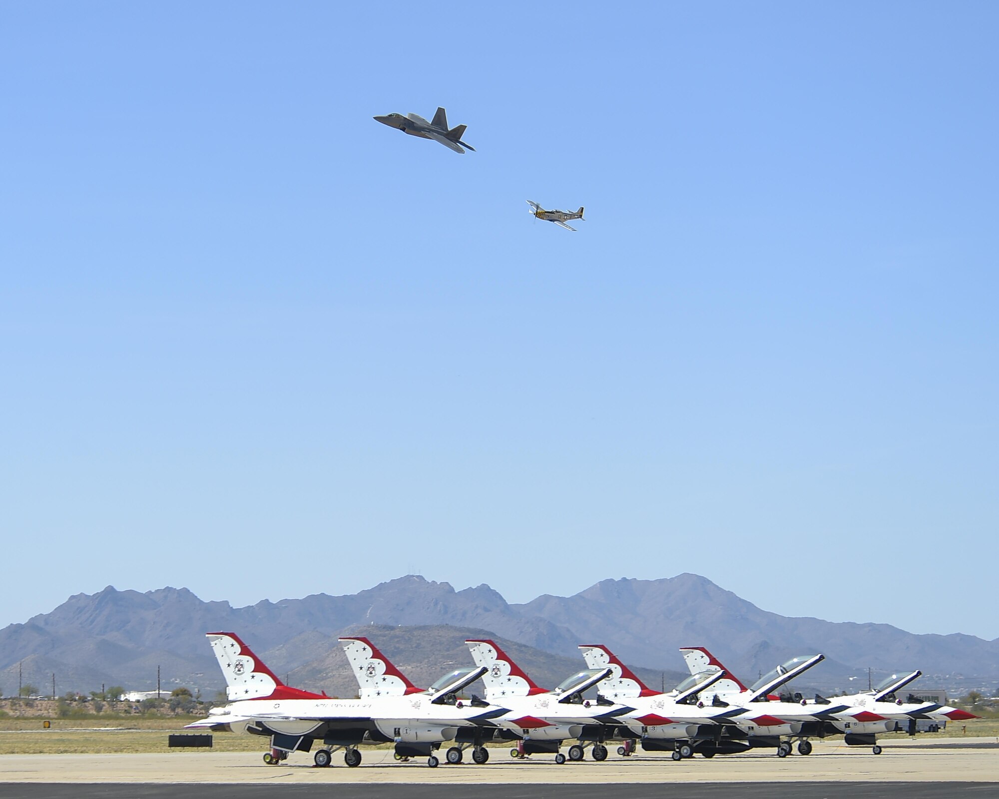 An F-22 Raptor and a P-51 Mustang perform “Heritage Flight” behind a row of Thunderbirds F-16 Fighting Falcons during the Thunder and Lightning over Arizona Open House at Davis-Monthan Air Force Base, Ariz., March 13, 2016. The open house featured aerial demonstrations from various teams and numerous static displays allowing the public to gain a better understanding of the Air Force. (U.S. Air Force photo by Senior Airman Chris Massey/Released)