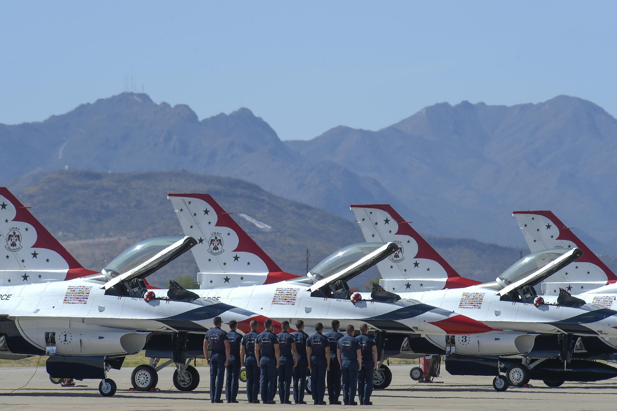 Members of the U.S. Air Force Air Demonstration Squadron air crew stand in formation before marching to their respective Thunderbird during the Thunder and Lightning over Arizona Open House event at Davis-Monthan Air Force Base, Ariz., March 13, 2016. For each Thunderbirds F-16 aircraft that travels, a crew chief and an assistant crew chief are assigned to it, ensuring their jet is always mission-ready. (U.S. Air Force photo by Senior Airman Chris Massey/Released)