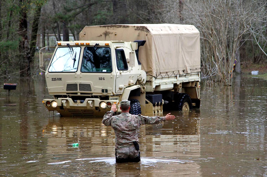 Army Sgt. David Breaud directs a high water vehicle down a flooded roadway at Latt Lake in Grant Parish, La., March 13, 2016. Breaud is assigned to the Louisiana National Guard’s Headquarters Company, 225th Engineer Brigade. Army National Guard photo by Staff Sgt. Jerry Rushing
