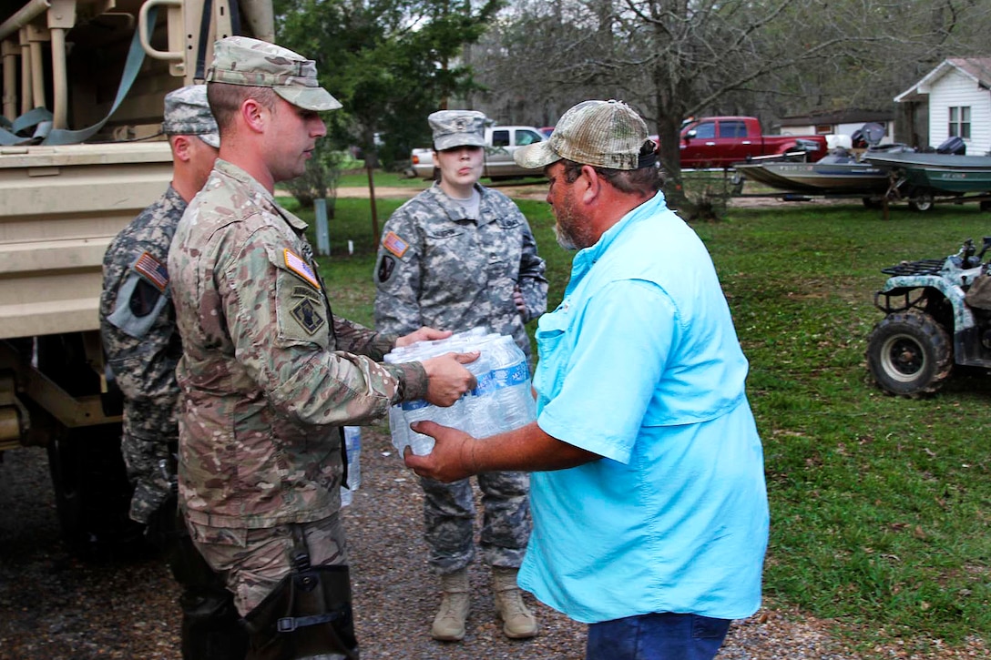 Sgt. David Breaud, left, assists the Grant Parish Sheriff's Office by distributing water to residents at Latt Lake in Grant Parish, La., March 13, 2016. Army National Guard photo by Staff Sgt. Jerry Rushing