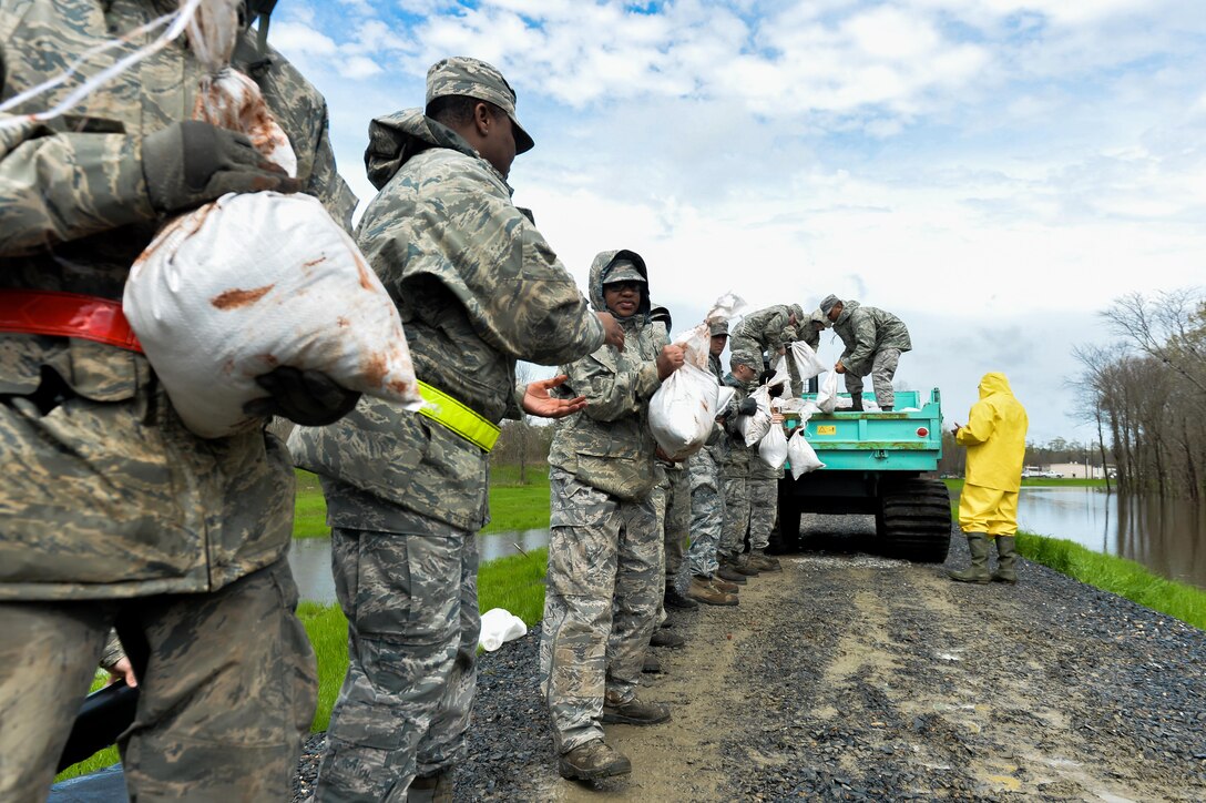 Airmen unload sandbags from a city vehicle in Bossier City, La., March 10, 2016. Airmen created a protective barrier over the Red Chute Bayou levee in an attempt to slow down corrosion caused by flooding in the Arkansas, Louisiana and Texas region. Air Force photo by Senior Airman Mozer O. Da Cunha