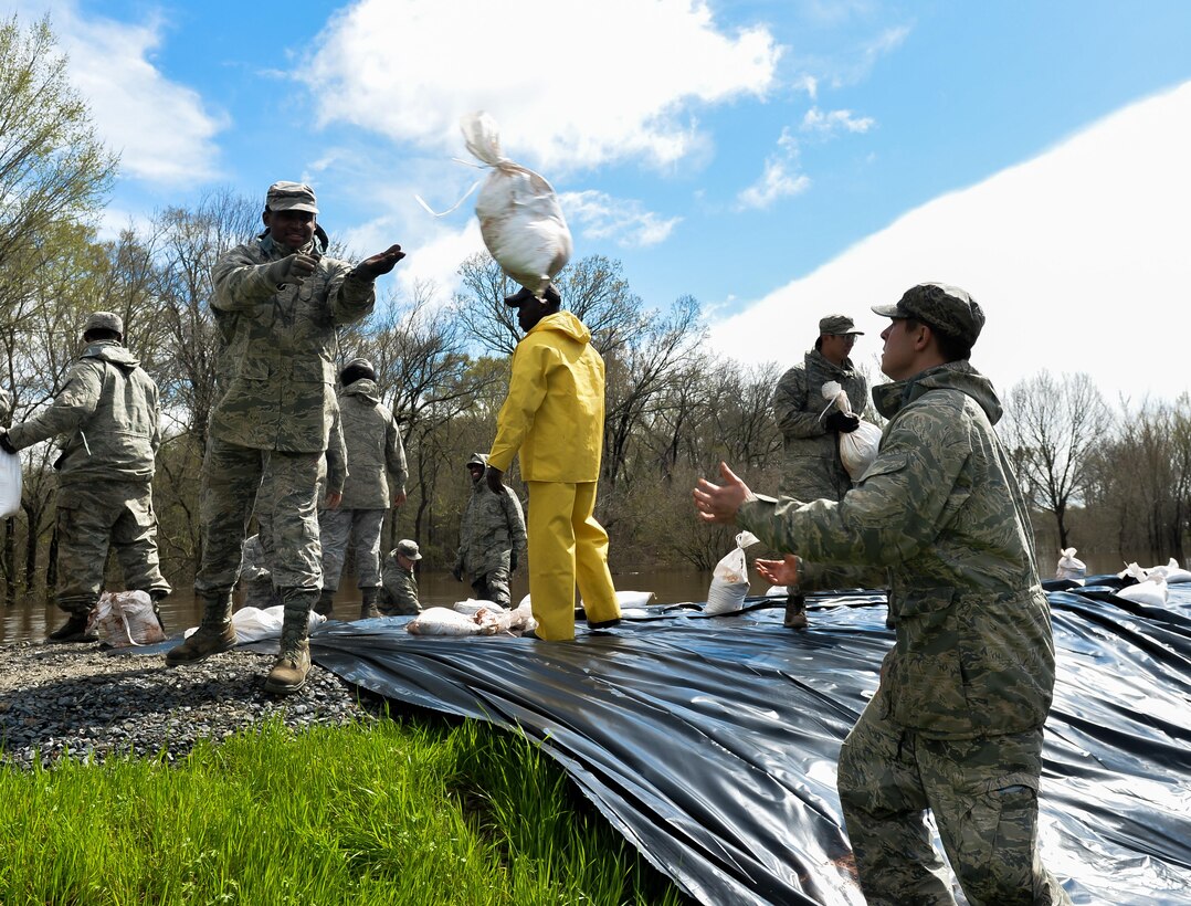 An airman throws a sandbag to his partner during the construction of protective flood barriers over the Red Chute Bayou levee in Bossier City, La., March 10, 2016. The airmen are assigned to the 2nd Logistics Readiness Squadron. Air Force photo by Senior Airman Mozer O. Da Cunha