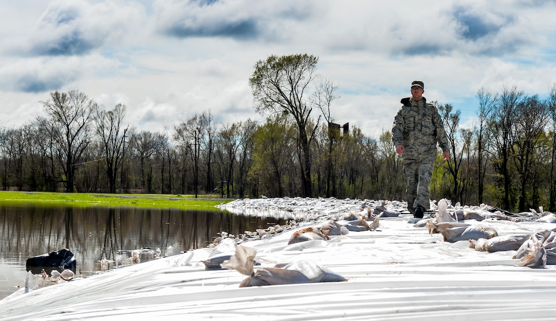 An airman surveys a newly covered portion of the levee in Bossier City, La., March 10, 2016. The plastic and sandbag barrier protected the Red Chute Bayou levee from potential corrosion caused by the overflowing river. The airmen are assigned to the 2nd Logistic Readiness Squadron. Air Force photo by Senior Airman Mozer O. Da Cunha