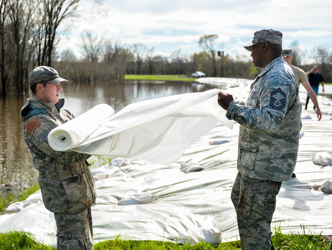 Airmen lay a plastic sheet over a levee in Bossier City, La., March 10, 2016. Plastic sheets kept water from reaching the top of the Red Chute Bayou levee and protected it from rain and rising waters. The airmen are assigned to the 2nd Logistics Readiness Squadron. Air Force photo by Senior Airman Mozer O. Da Cunha