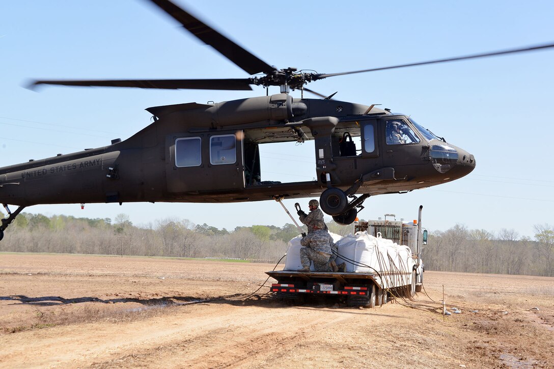 Soldiers slingload 1,500-pound sacks of sand under a UH-60 Black Hawk helicopter in Bayou Darrow in Grant Parish, La., March 14, 2016. The helicopter crew is assigned to an Army aviation facility in Pineville, La. More than 1,400 Guardsmen have participated in flood support missions across Louisiana. Louisiana National Guard photo by 1st Lt. Rebekah Malone