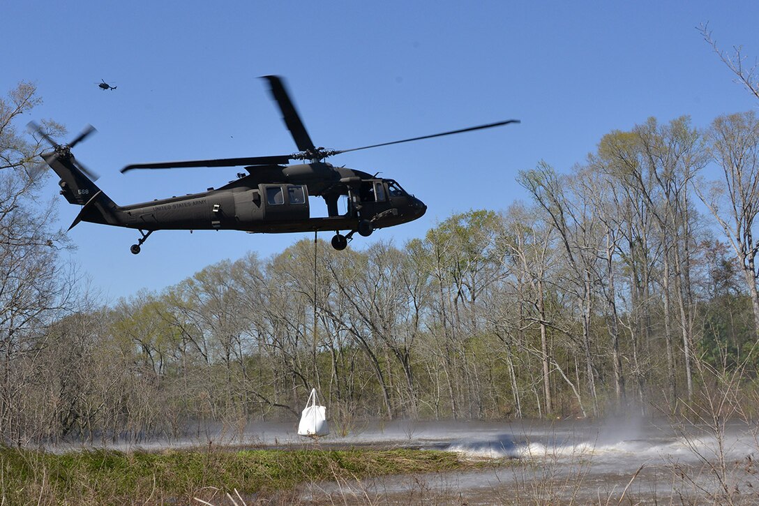 A UH-60 Black Hawk helicopter prepares to drop sacks of sand into Bayou Darrow in Grant Parish, La., March 14, 2016, to slow the flow of water where a control structure failed. Louisiana National Guard photo by 1st Lt. Rebekah Malone