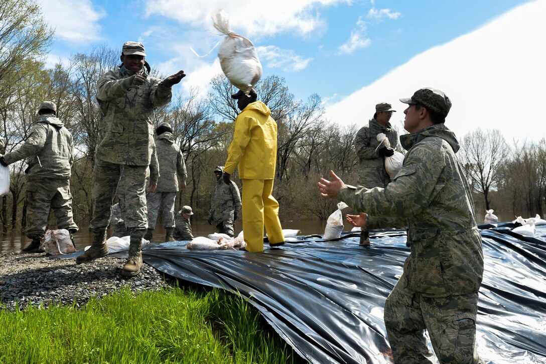 An airman throws a sandbag to his partner during the construction of protective flood barriers over the Red Chute Bayou levee in Bossier City, La., March 10, 2016. The airmen are assigned to the 2nd Logistics Readiness Squadron. Air Force photo by Senior Airman Mozer Da Cunha

