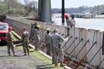 More than 15 Louisiana National Guard members from the 1022nd Engineer Company and the 844th Engineer Company out of West Monroe are assembling emergency levee walls on the banks of the Ouachita River in Monroe on March 13, 2016, to protect the city from rising river levels caused by excessive rainfall. The Soldiers are working in conjunction with the Tensas Levee Basin District to transform half a mile of hinged concrete slabs, which are usually the sidewalk alongside the river, into a six-foot tall levee. 