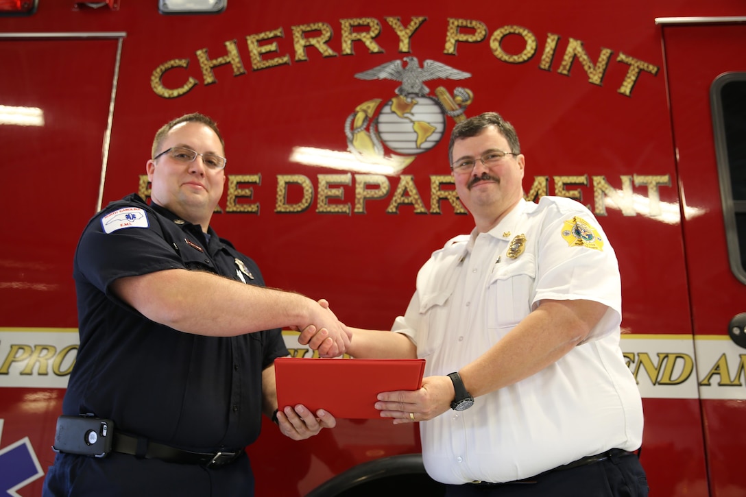 Dustin J. Schneider, left, accepts the Marine Corps Civilian Firefighter of the Year Award from fire chief Rodney T. Wade at Marine Corps Air Station Cherry Point, N.C., March 3, 2016. Schneider earned the award for excellence in his job performance. Schneider was chosen from firefighters in fire departments across the Marine Corps. Schneider serves with Cherry Point Fire and Emergency Services. (U.S. Marine Corps photo by Lance Cpl. Mackenzie Gibson/Released)