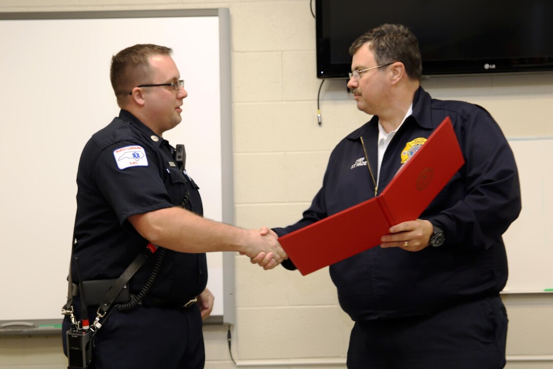 Dustin J. Schneider, left, accepts the Marine Corps Firefighter of the Year Award from fire chief Rodney T. Wade at Marine Corps Air Station Cherry Point, N.C., March 3, 2016. Schneider earned the award for excellence in his job performance. Schneider was chosen from firefighters in fire departments across the Marine Corps. Schneider serves with Cherry Point Fire and Emergency Services. (U.S. Marine Corps photo by Lance Cpl. Mackenzie Gibson/Released)