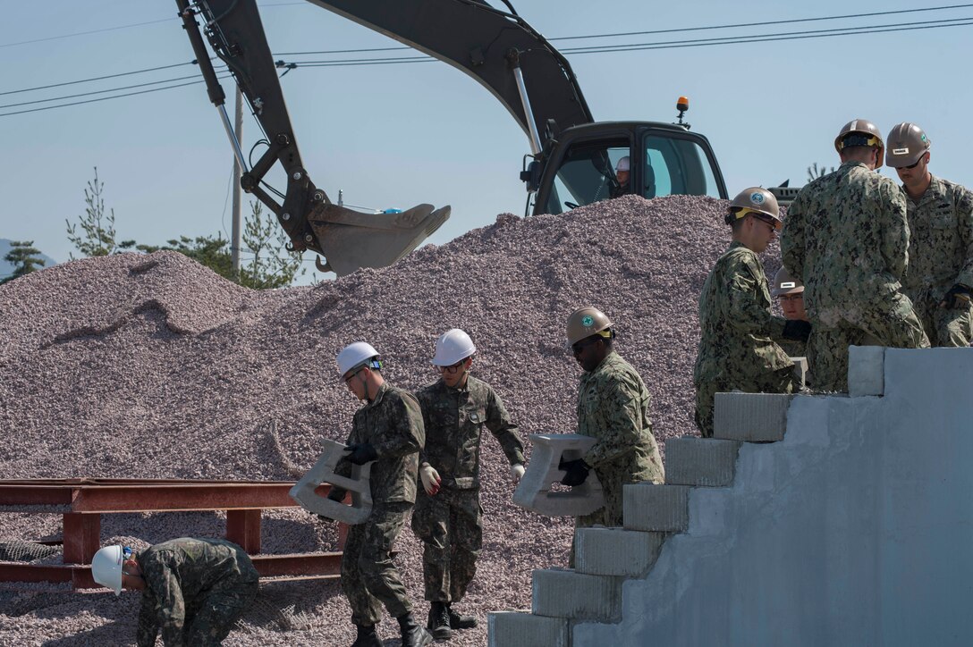 U.S. Navy Seabees assigned to Naval Mobile Construction Battalion 4, and South Korean Seabees move concrete blocks and aggregate during pier repair training as part of exercise Foal Eagle 2016 in Jinhae, South Korea, March 15, 2016. Navy photo by Chief Lowell Whitman