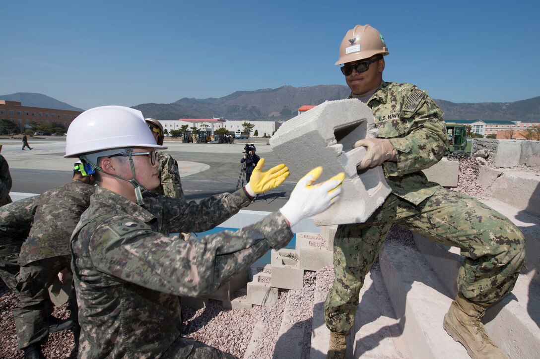 U.S. Navy Petty Officer 3rd Class Brian Rosette, assigned to Naval Mobile Construction Battalion 4, passes a concrete block to a South Korean Seabee during pier repair training as part of exercise Foal Eagle 2016 in Jinhae, South Korea, March 15, 2016. Navy photo by Chief Lowell Whitman