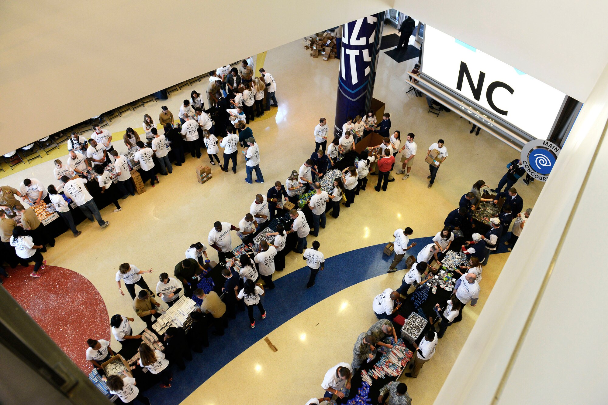 U.S. troops and civilian volunteers organize a deployment kit processing table at a military care event at Time Warner Cable Arena, Charlotte, N.C., March 8, 2016. With service member and civilian volunteer efforts, over 10,000 deployment kits were packed with deployment-essentials including toothpaste, medicine, socks, and other items. (U.S. Air Force photo by Airman 1st Class Christopher Maldonado)