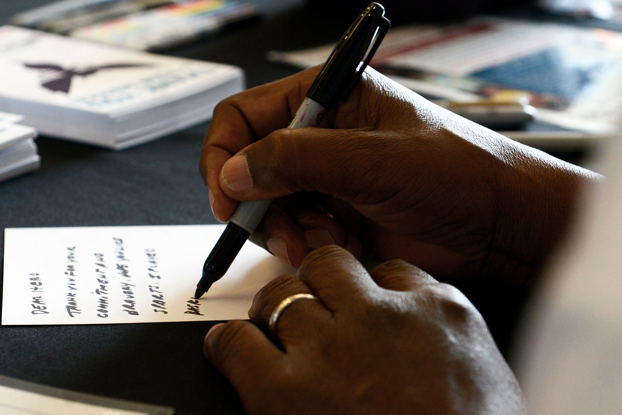 A volunteer writes a thank you card for a deployed service member during a military care event at Time Warner Cable Arena, Charlotte. N.C., March 8, 2016. Throughout the event, volunteers were given the opportunity to write thank you cards to the many men and women deployed overseas. (U.S. Air Force photo by Airman 1st Class Christopher Maldonado)