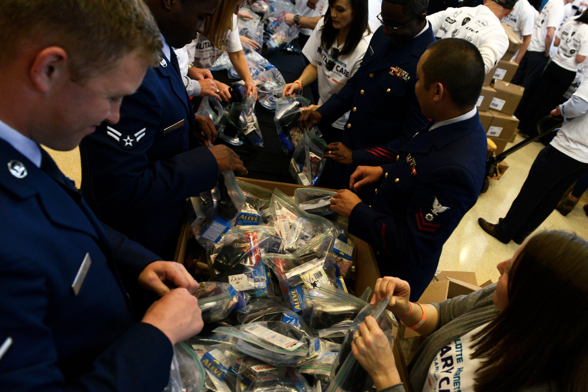 U.S. Airmen and U.S. Coast Guardsmen aid civilian volunteers in the assembly of deployment kits at Time Warner Cable Arena, Charlotte, N.C., March 8, 2016. Service members worked together with over 300 volunteers to assemble more than 10,000 deployment kits with deployment essential amenities. (U.S. Air Force photo by Airman 1st Class Christopher Maldonado) 