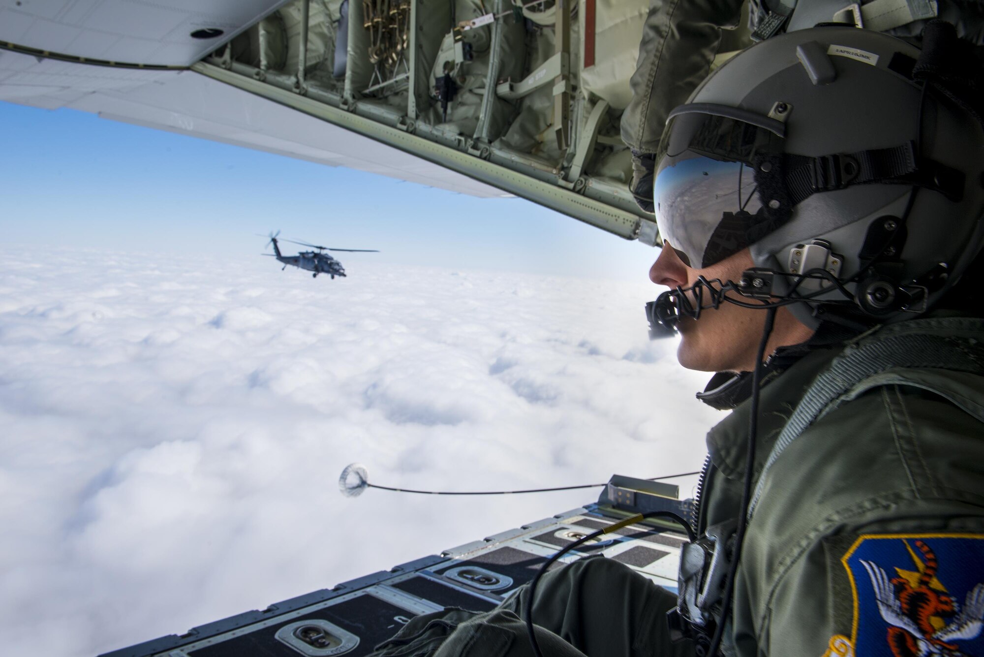 U.S. Air Force Staff Sgt. Colleen McGahuey-Ramsey, 71st Rescue Squadron loadmaster, watches an HH-60G Pave Hawk after aerial refueling operations, Mar. 4, 2016, over Moody Air Force Base, Ga. Multiple aircraft within Air Combat Command conducted joint aerial training that showcased the aircrafts tactical air and ground maneuvers, as well as its weapon capabilities. (U.S. Air Force photo by Senior Airman Ryan Callaghan/Released)

