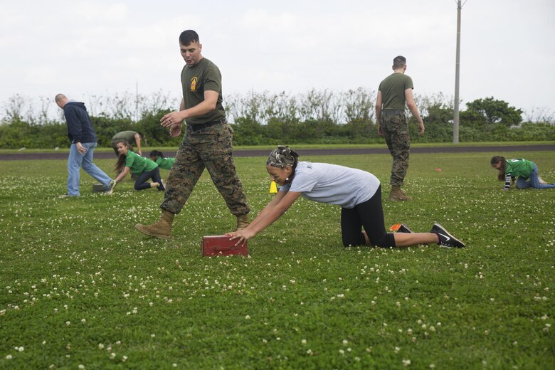 Sgt. Giles A. Decker encourages a member of Girl Scout Troop 435 during a modified combat fitness test during a Jane Wayne Day March 12 aboard Camp Kinser, Okinawa, Japan. Jane Wayne Day is an event designed to allow spouses and children to gain a better understanding of some of the physical challenges military service members face. Girl Scout Troop 435 attended in celebration of the Girl Scouts’ 104th Birthday and learned about radios, the Marine Corps Martial Arts Program, ran a modified combat fitness test, perused medical equipment and donned chemical, biological, radiological, nuclear defense equipment. Decker is a warehouse clerk with Supply Company, Combat Logistics Regiment 35, 3rd Marine Logistics Group, III Marine Expeditionary Force and an East Stroudsburg, Pennsylvania, native.