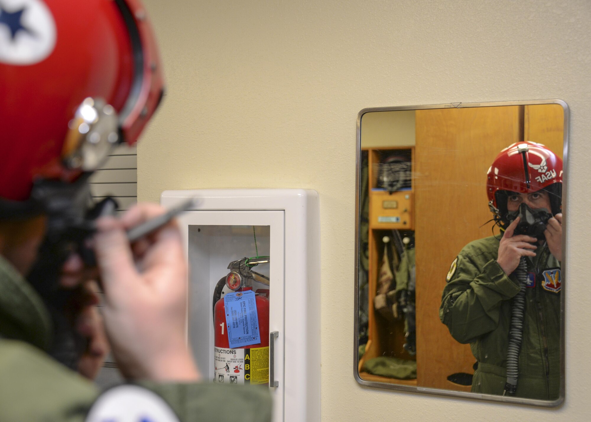 Brendan Lyons, Tucson community hometown hero, uses a mirror to practice securing an oxygen mask to a helmet prior to his flight in an F-16 Fighting Falcon, from the U.S. Air Force Air Demonstration Squadron, at Davis-Monthan Air Force Base, Ariz., March 11, 2016.  Lyons was nominated as a hometown hero to fly with the Thunderbirds because of his commitment to safety and his passion to make Tucson a safer community for cyclists and motorists.  (U.S. Air Force photo by Senior Airman Chris Massey/Released)