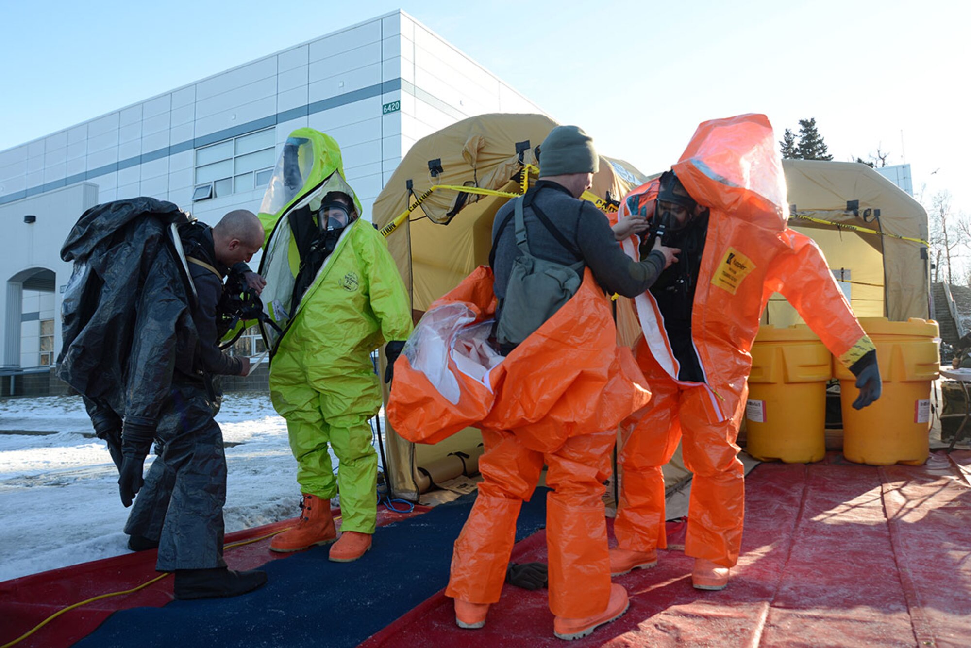 Members of the Alaska National Guard’s 103d Civil Support Team receive help removing their suits after decontamination during their technical proficiency evaluation test for federal recognition as a regional chemical, biological, radiological and nuclear response unit in Anchorage, Alaska, Feb. 16, 2016. (U.S. Air Force photo by Airman 1st Class Christopher R. Morales)