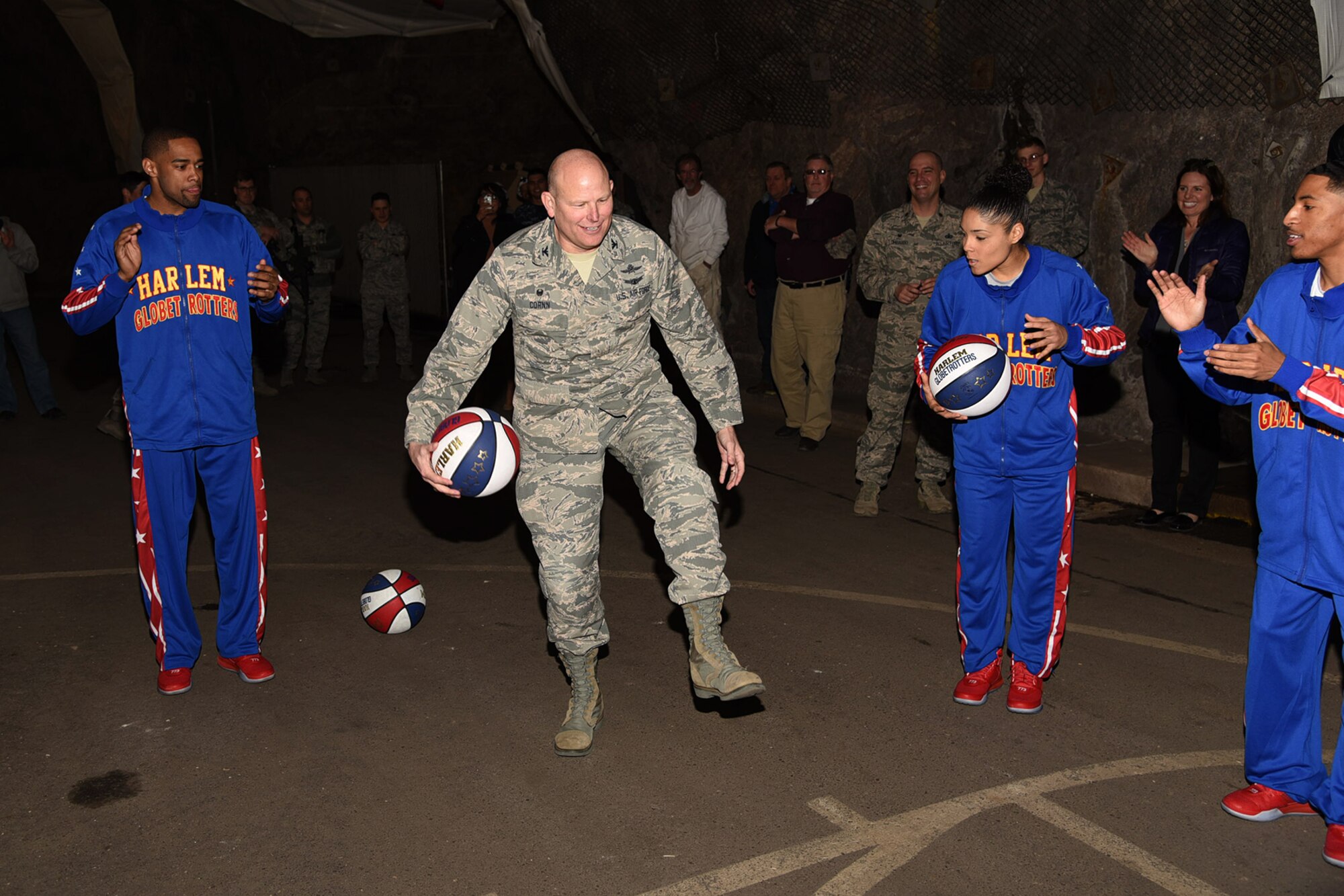 PETERSON AIR FORCE BASE, Colo. - Col. Gary L. Cornn, Jr., 721st Mission Support Group and Cheyenne Mountain Air Force Station installation commander, learns dribbling tricks from the Harlem Globetrotters during a visit and tour here March 10, 2016. The Globetrotters, who are celebrating their 90th year, visited and toured “Behind the Blast Doors” as part of the CMAFS ongoing 50th Anniversary celebration. (U.S. Air Force photo by Robb Lingley)