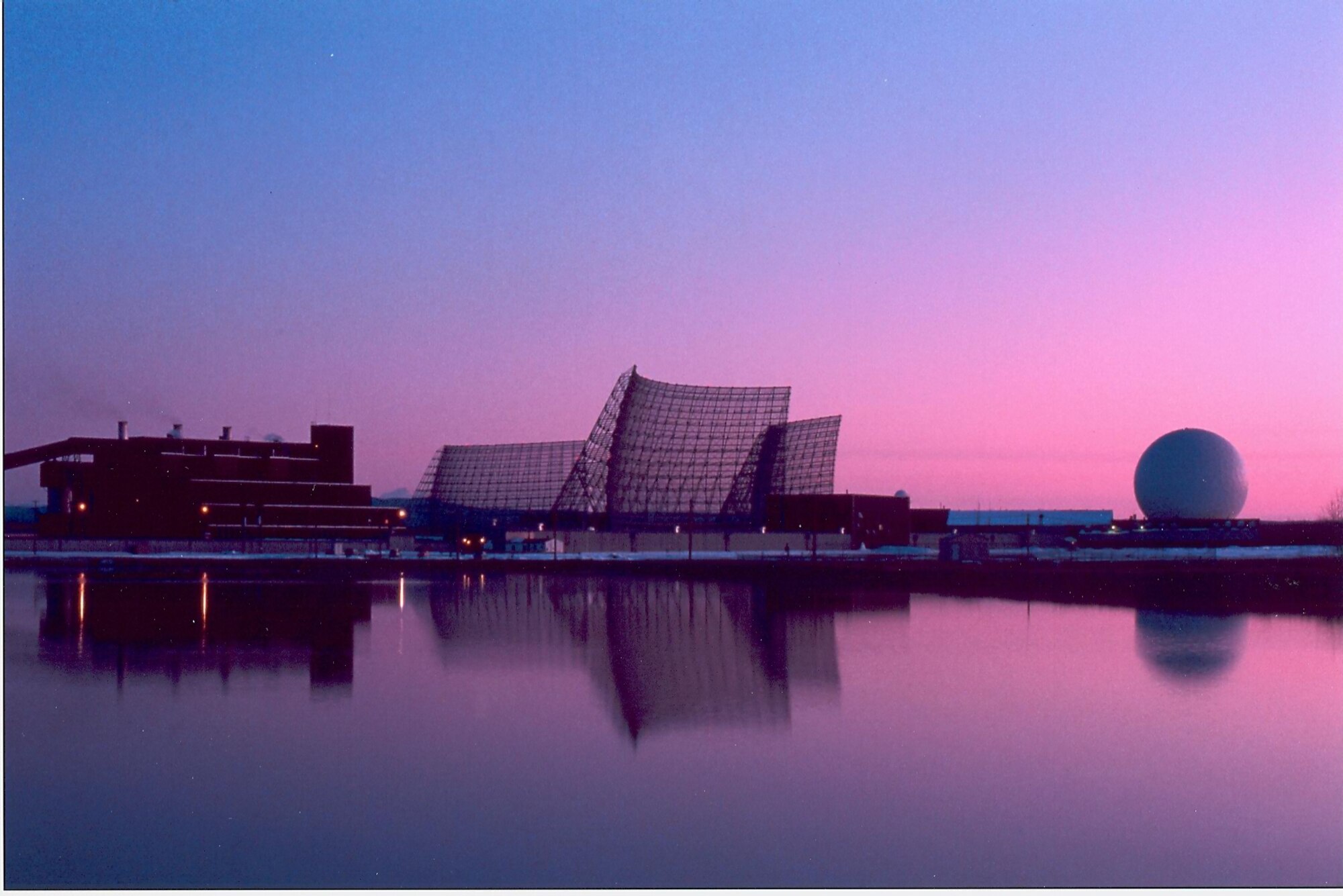 CLEAR AIR FORCE STATION, Alaska – Rising from the Alaskan interior the coal power plant, left, and the Ballistic Missile Early Warning System radar, now replaced in service by a Solid State Phased Array Radar System, are silhouetted by the rising sun over Clear AFS.(Courtesy photo)