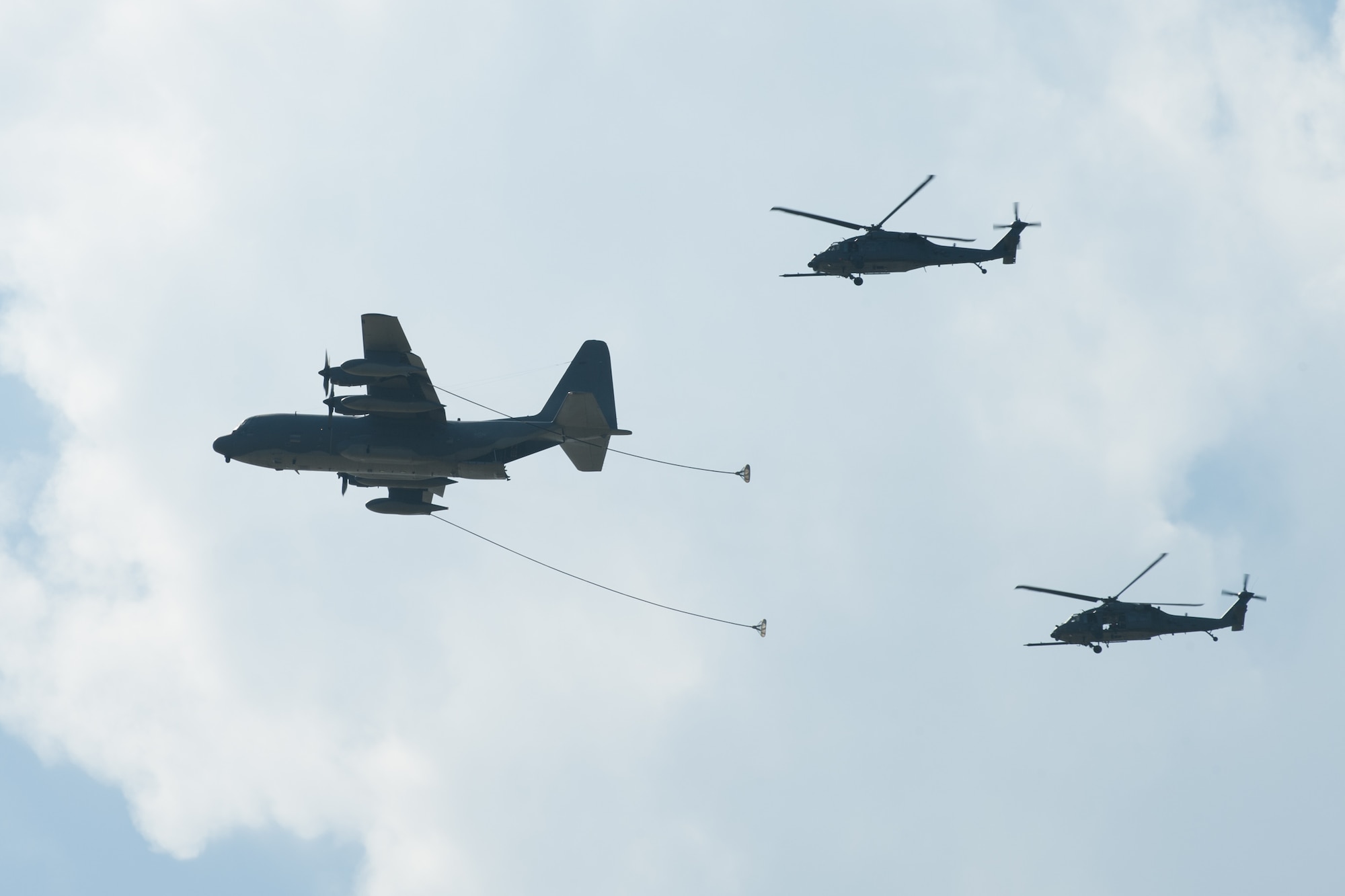 An HC-130P/N King crew flies in formation with the two HH-60 Pave Hawk helicopters to showcase its aerial refueling capabilities during an astronaut rescue demonstration at Patrick Air Force Base, Fla., March 14, 2016. The demonstration involved Air Force Guardian Angel Airmen and aircraft from the 920th Rescue Wing to showcase aspects of safe rescue operations. Airmen from Detachment 3 coordinate astronaut capsule rescue and recovery and train personnel worldwide to ensure the Department of Defense is ready to support NASA's human space endeavors. (U.S. Air Force photo by Benjamin Thacker/Released)