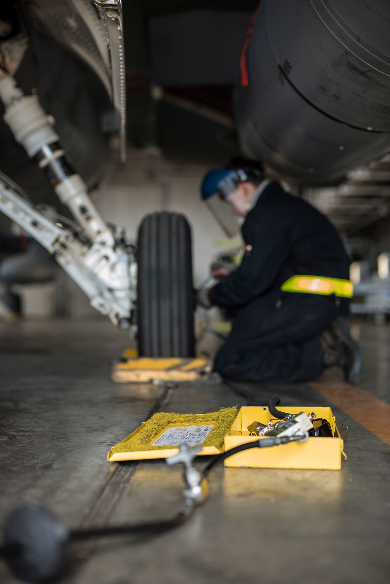 A tire pressure valve box sits on the ground while Senior Airman Bradley Poirier, a crew chief with the 14th Aircraft Maintenance Squadron, fills an F-16 Fighting Falcon tire with air at Misawa Air Base, Japan, March 15, 2016. Making sure the tires are filled to the correct pressure is crucial, as over or under filling the tires can cause serious injury to personnel and assests. (U.S. Air Force photo by Senior Airman Brittany A. Chase)