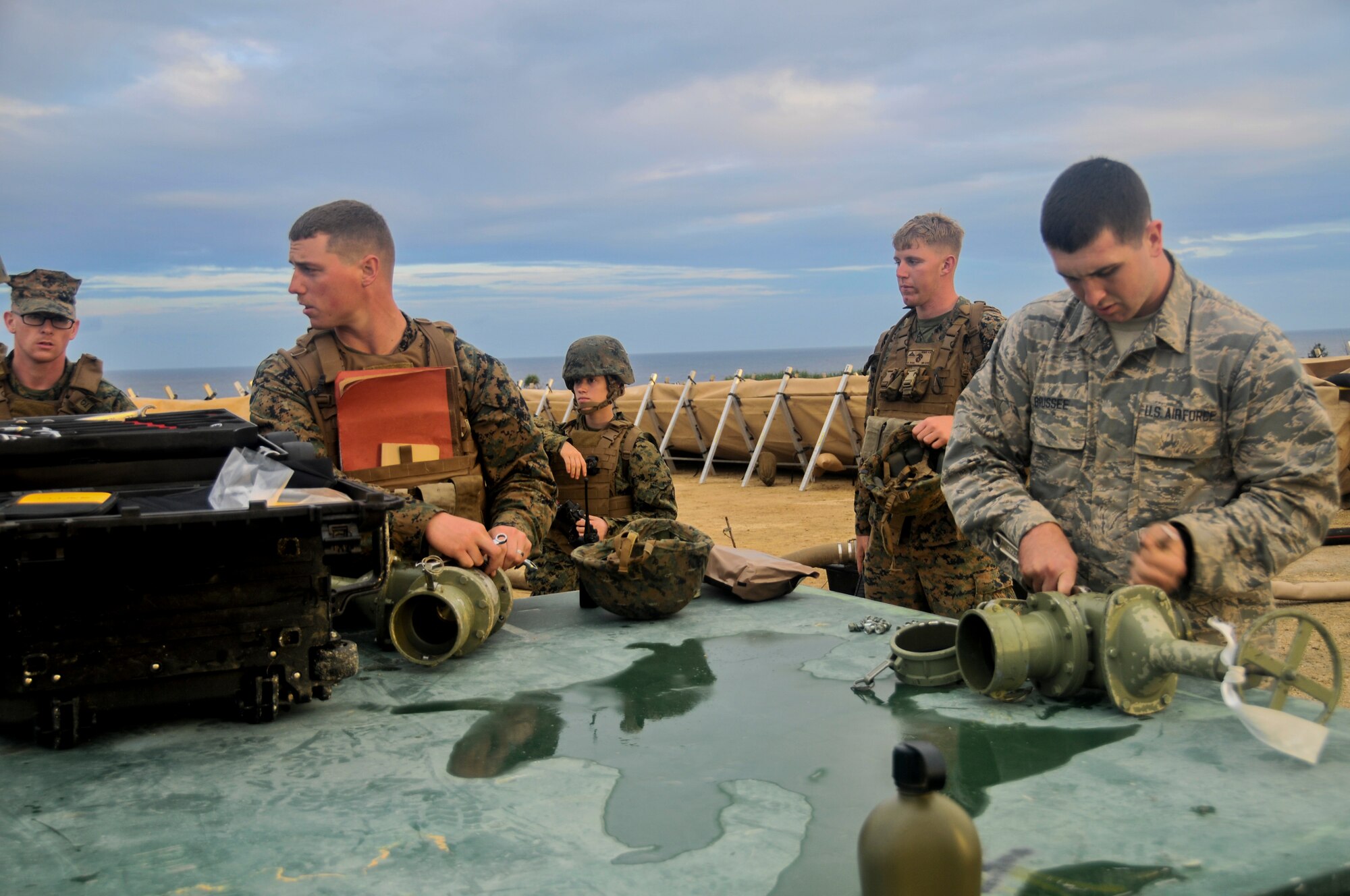 U.S. Marine Corps engineers assigned to the 9th Engineer Support battalion and Airmen from the 18th Logistics readiness squadron perform maintenance on an amphibious assault fuel system during an exercise Jan. 29, 2016, on the island of Ie Shima off the coast of Okinawa, Japan.  The field exercise allowed Marines and Airmen to experience a joint environment and share different methods and techniques from their fellow servicemen and women. (Courtesy photo) 