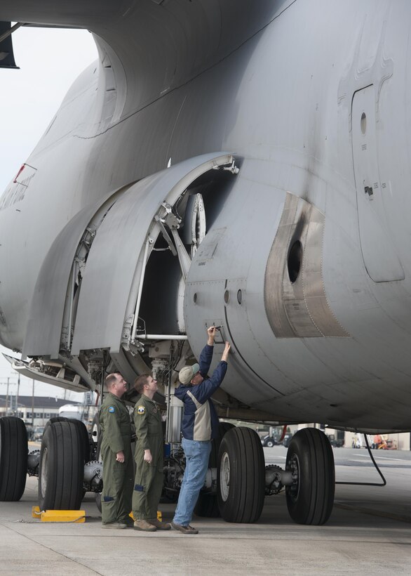 Ralph Kellenberger, FlightSafety flight engineer instructor, walks Tech. Sgt. Ryan Berry, 312th Airlift Squadron flight engineer, and Master Sgt. James Spinner, 9th AS flight engineer, through C-5M Super Galaxy pre-fight procedures during initial qualification training March 10, 2016, at Dover Air Force Base, Del. FlightSafety operates on Dover AFB as a contractor that trains Air Force pilots and flight engineers. (U.S. Air Force photo/Senior Airman Zachary Cacicia)