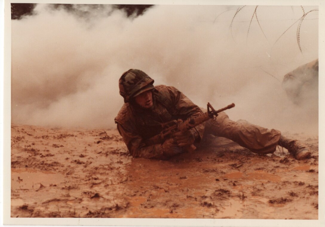 c. 1980. This Reserve Marine crawls through mud and smoke to advance on an enemy position during a training exercise.