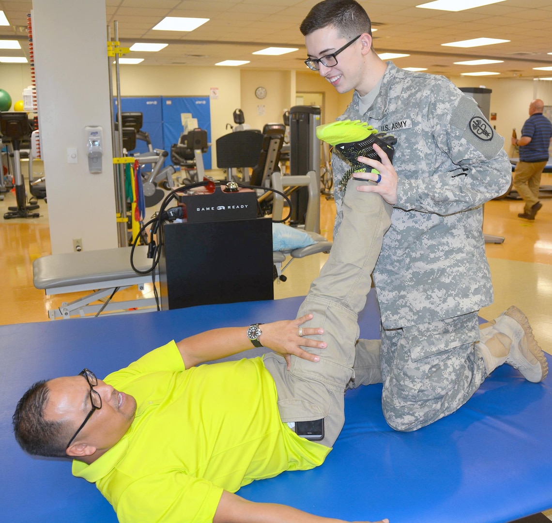 Pfc. Cole Blancett (right), physical therapy assistant, helps Douglas Biala stretch during a physical therapy appointment March 6 at the Capt. Jennifer M. Moreno Primary Care Clinic at Fort Sam Houston. Two physical therapists and two physical therapy assistants are available by appointment from 4:30 p.m. to 7:30 p.m. Monday through Thursday.