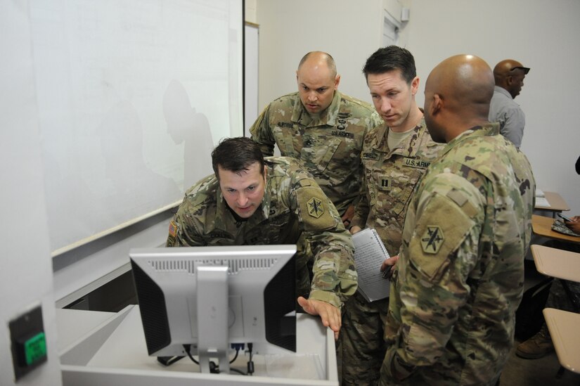 Cpt. Michael Collins,  Staff Sgt. Matthew Woods, Cpt. John Capiello, and Sgt. 1st Class Diego Piña prepare to brief ROTC student at the Inter American University of Puerto Rico – Arecibo as part of their training during Operation Coqui. The purpose of the brief was for the CA teams to practice their Spanish fluency skills while informing ROTC students on what Civil Affairs is and answer any questions they may have.