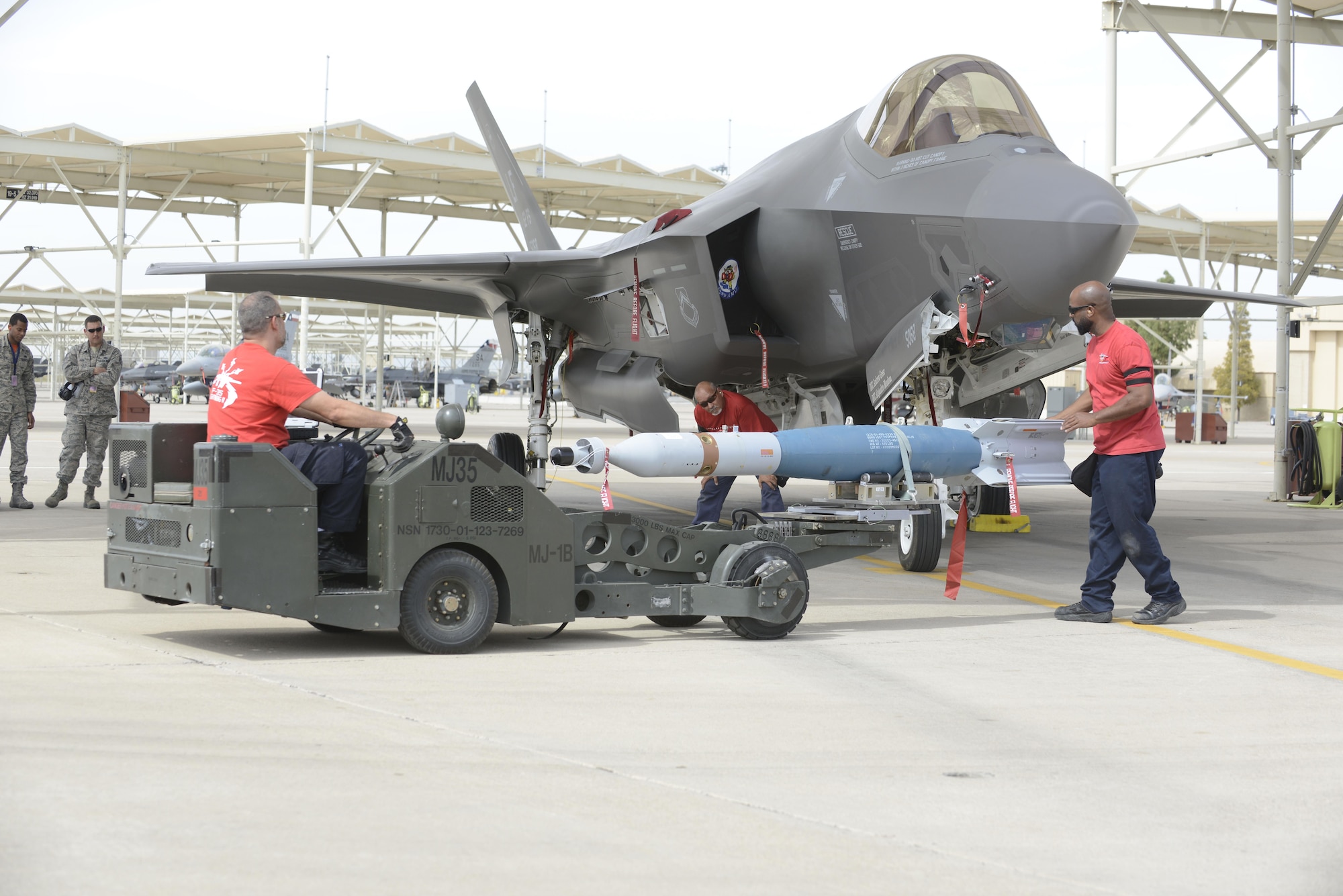 Weapons load crew members from the 62nd Aircraft Maintenance Unit load laser-guided bombs onto an F-35 Lightening II March 11, 2016 at Luke Air Force Base, Ariz. The F-35A Lightning II program took another step toward initial operational capability yesterday when two aircraft assigned to the 62nd Fighter Squadron successfully employed four laser guided bombs on the Barry M. Goldwater Range. The maintenance load crew team was comprised of Lockheed Martin contractors. (U.S. Air Force Photo by Senior Airman Devante Williams)
