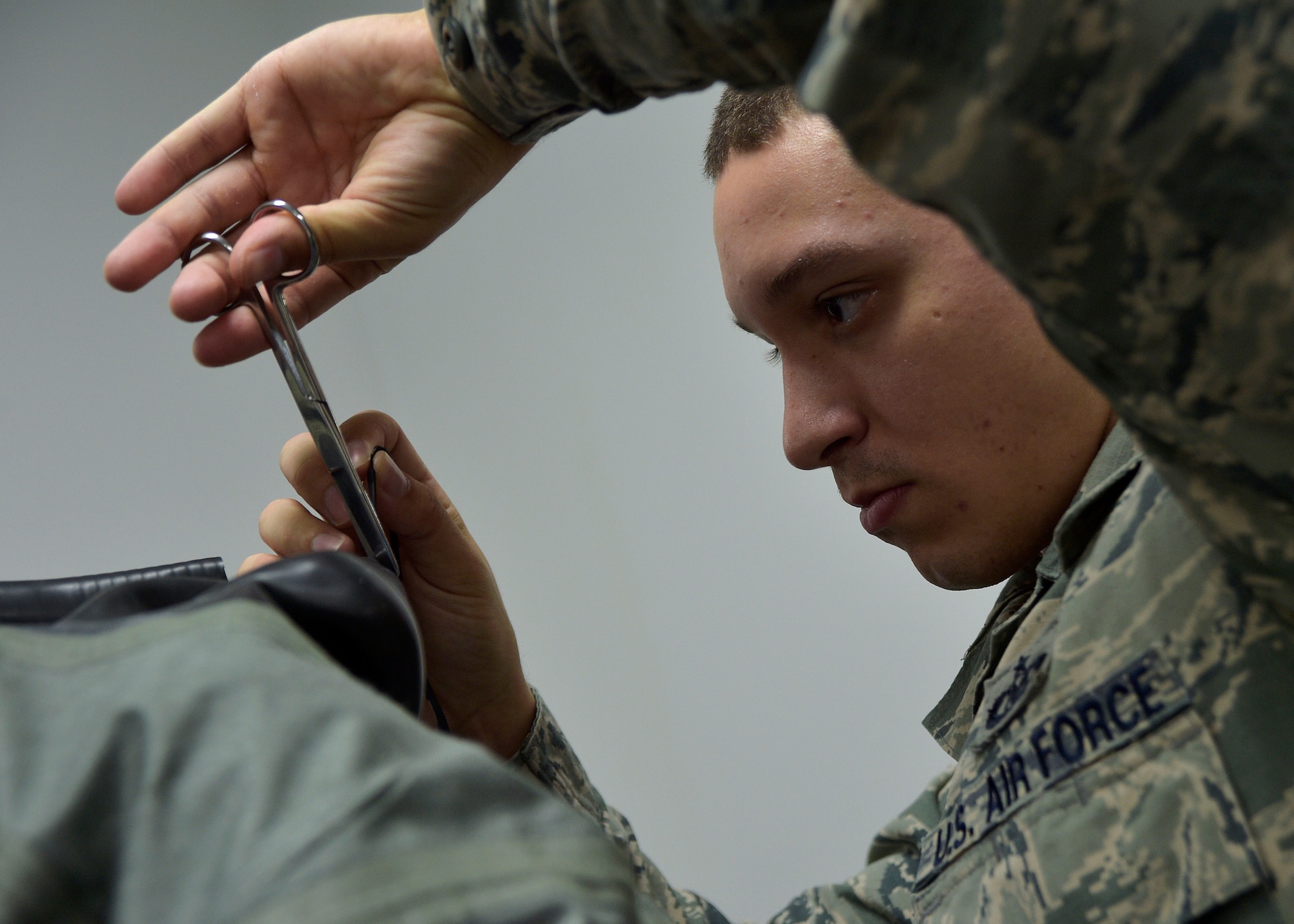 U.S. Air Force Staff Sgt. James Berg, an aircrew flight equipment craftsman with the 35th Operations Support Squadron, cuts a rubber ring off a suit at Misawa Air Base, Japan, March 8, 2016. An off-the-side suit is used during the winter months or when pilots are flying over water. (U.S. Air Force photo by Senior Airman Deana Heitzman)