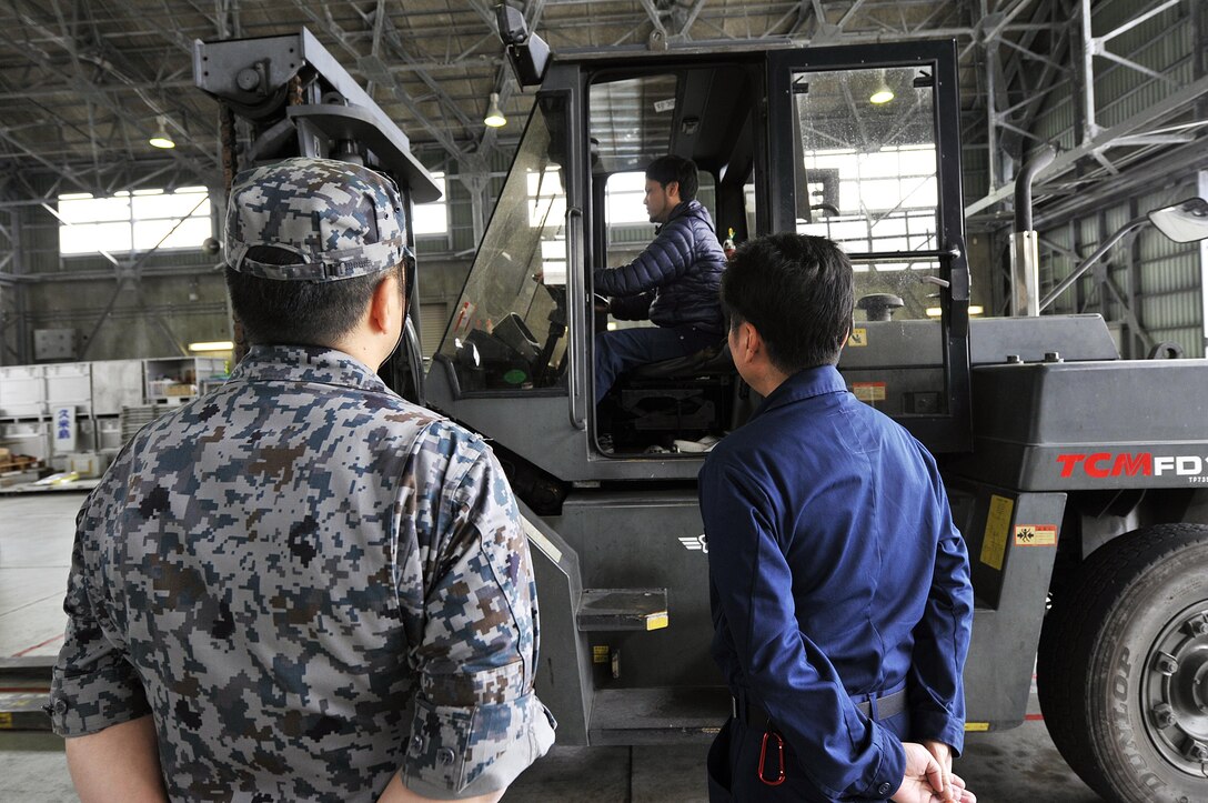 Takumi Noborikawa, 733rd Air Mobility Squadron electric equipment repair technician, examines a Japan Air Self-Defense Force TMC FD100 forklift during a tour, March 10, 2016, at Naha Air Base, Japan. JASDF provided an opportunity for 24 members from the 733rd Air Mobility Squadron to gain a better understanding of the JASDF side of Aerial Port operations. (U.S. Air Force photo by Naoto Anazawa)

